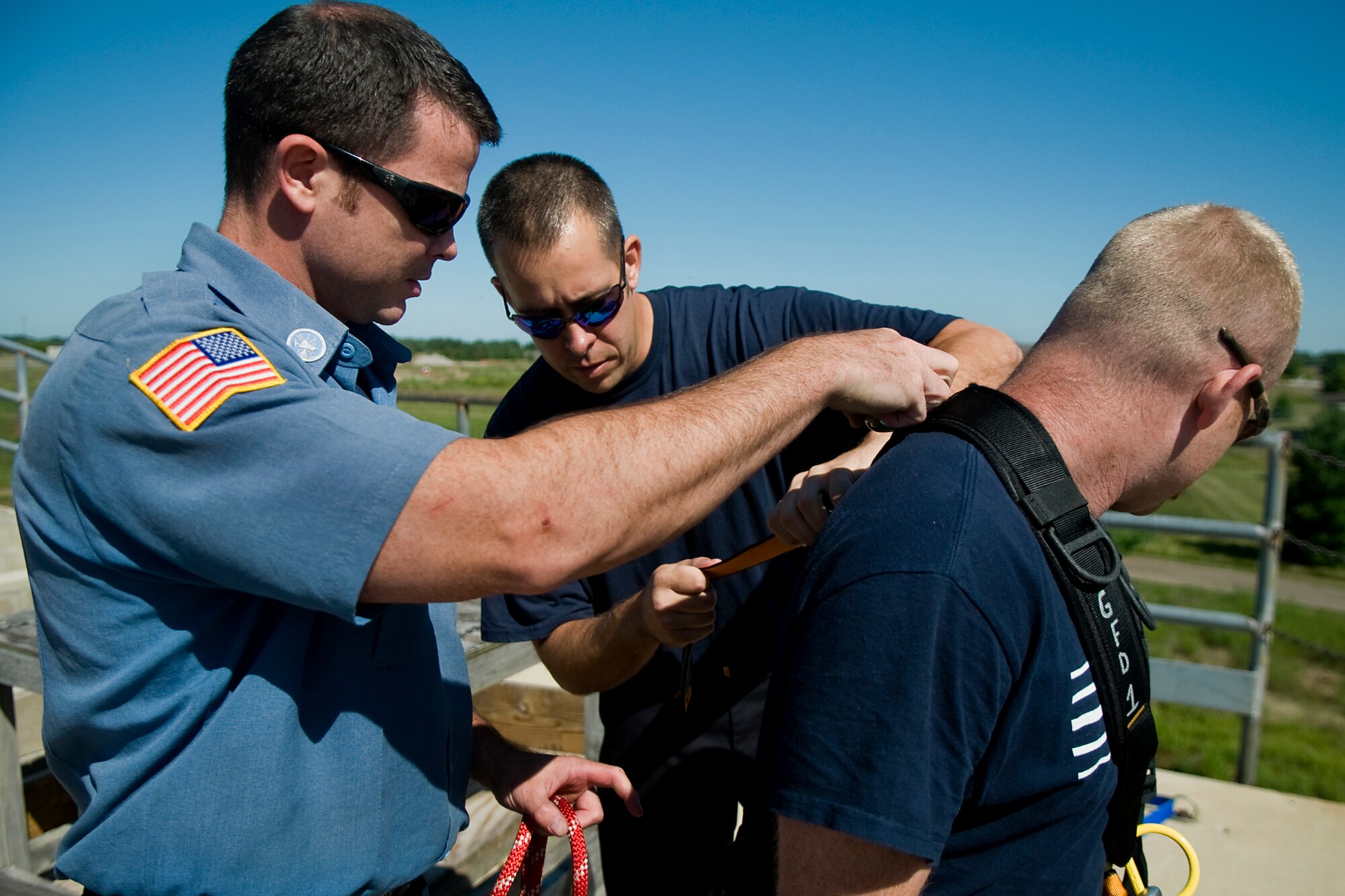 From left, Robert Jacobs and Capt. Jay Salmons, and secure a harness on Jamie Lay prior to Lay rappelling down a fire training tower at Grissom Air Reserve Base, Ind., Aug. 15, 2014. All three are firefighters with the Grissom Fire Department. (U.S. Air Force photo/Tech. Sgt. Mark R. W. Orders-Woempner) 
