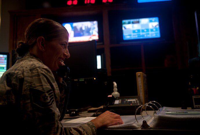 Tech. Sgt. Laura Langley, 99th Air Base Wing Command Post senior controller, shares a laugh on the phone while a running a range fire condition checklist at Nellis Air Force Base, Nev., Aug. 21, 2014. Command post controllers run multiple checklists throughout their 12-hour shift, and have a checklist on deck to aid them in handling any situation that could occur. (U.S. Air Force photo by Staff Sgt. Siuta B. Ika)