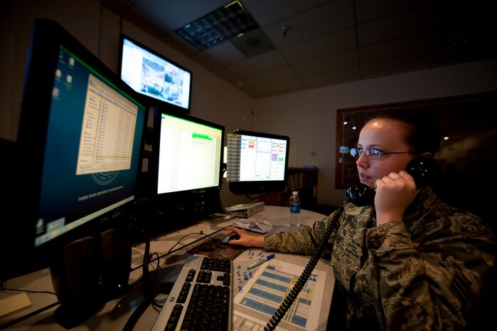 Senior Airman Sarah Myers, 99th Air Base Wing Command Post junior controller, prepares to open a report while fielding a phone call at Nellis Air Force Base, Nev., Aug. 21, 2014. Myers and other controllers in the command post are responsible for receiving and disseminating hazardous weather alerts, in-flight emergency notifications, and installation security concerns to numerous agencies on base, and if needed, to leadership at the Air Combat Command and Air Force levels. (U.S. Air Force photo by Staff Sgt. Siuta B. Ika)