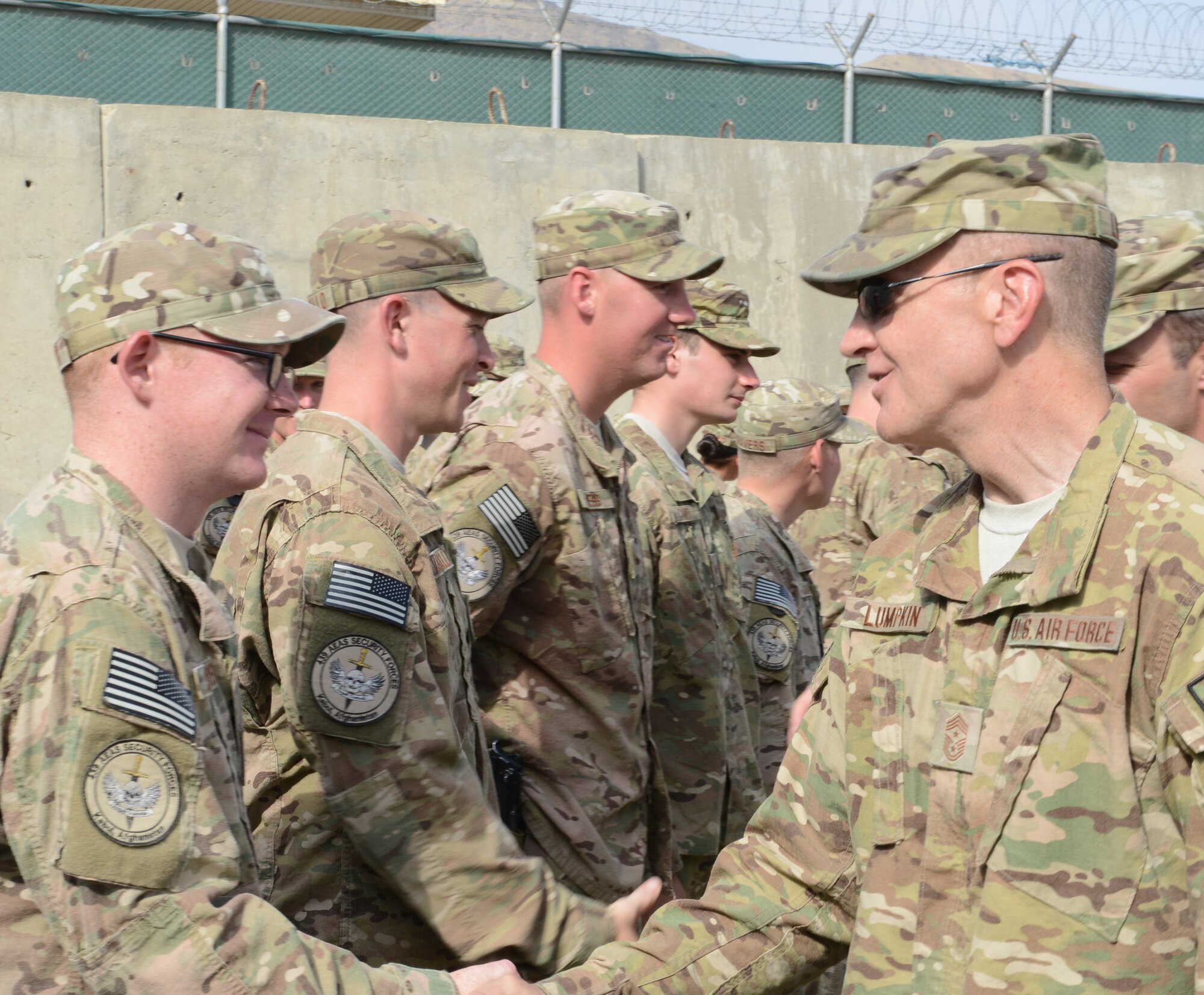 NATO Air Training Command-Afghanistan and 438th Air Expeditionary Wing command chief, Chief Master Sgt. Scott Lumpkin, congratulates Staff Sgt. Cody Shearer after Shearer and 38 other members of the 439th Air Expeditionary Advisory Squadron security forces were awarded the Air Force Combat Action Medal in a ceremony at Forward Operating Base Oqab, Afghanistan, Sept. 2, 2014. The Air Force recognized the Airmen for their service during a more than five-hour firefight against Taliban-linked insurgents attacking the base and adjacent bases July 17, 2014. (U.S. Air Force photo/Senior Master Sgt. Mike Hammond)