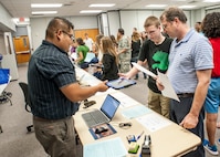 Jose Lopez (left), Randolph Field Independent School District technology department representative, issues an iPad to Ethan Chappel (center), Randolph High School sophomore, as George Chappel, Ethan's father, looks on. (U.S. Air Force photo by Melissa Peterson)