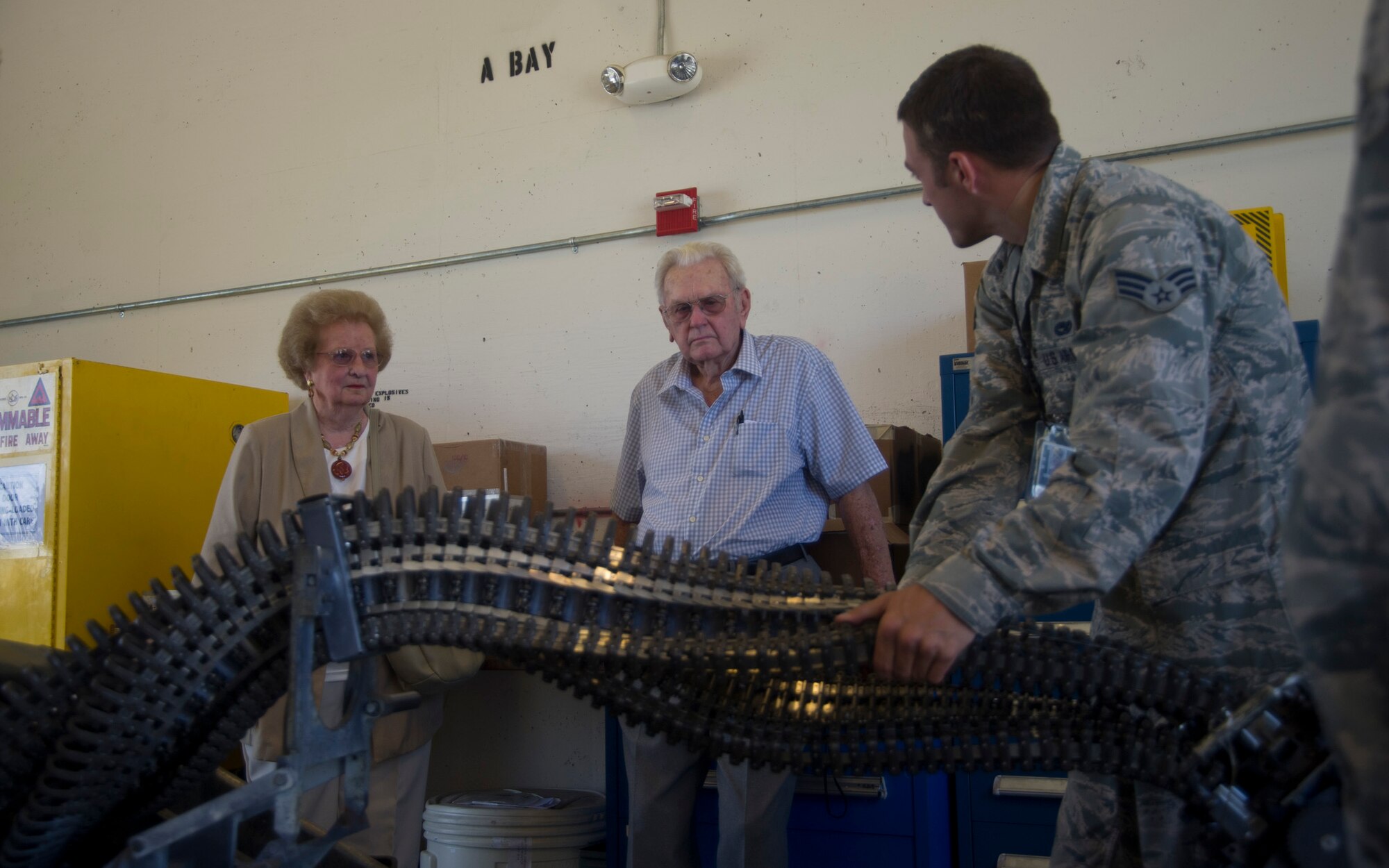 Ed and Mary Butzke watch as Senior Airman Cameron Kidd, 325th Maintainence Squadron munitions conventioanl maintainence crew chief, gives a hands-on demo of how aircraft bullets are loaded Aug. 25. This was the job that Mary preformed here in 1942. (U.S. Air Force photo by Airman 1st Class Dustin Mullen)