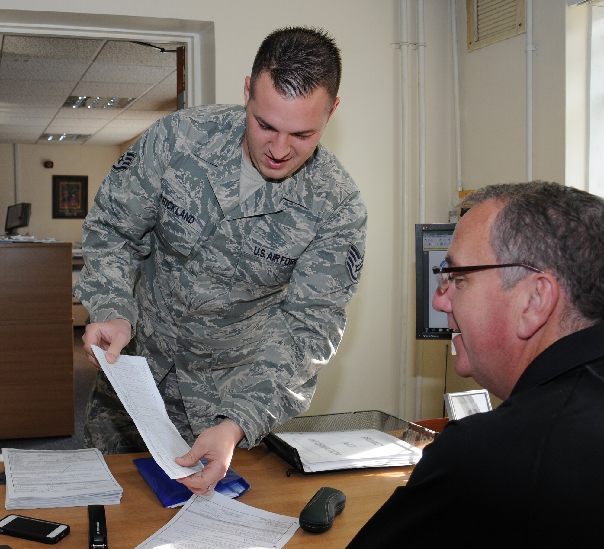 U.S. Air Force Staff Sgt. Michael Strickland, left, 100th Logistics Readiness Squadron U-Drive-It dispatcher from Myrtle Beach, S.C., discusses an operator’s monthly requirement form with Michael Cooper, 100th LRS chief dispatcher from Dublin, Ireland, Aug. 1, 2014, on RAF Mildenhall, England. Strickland’s team distributes vehicles to different people on base if the request is for official use. He also arranges vehicles to use for visits by distinguished visitors. (U.S. Air Force photo/Gina Randall/Released) 