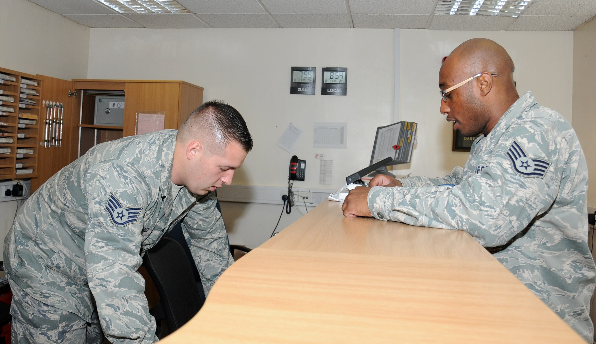 U.S. Air Force Staff Sgt. Michael Strickland, left, 100th Logistics Readiness Squadron U-Drive-It dispatcher from Myrtle Beach, S.C., assists a customer with a request Aug. 1, 2014, on RAF Mildenhall, England. Strickland’s team distributes vehicles to different people on base if the request is for official use. He also deals with the vehicles for visits by distinguished visitors. (U.S. Air Force photo/Gina Randall/Released)