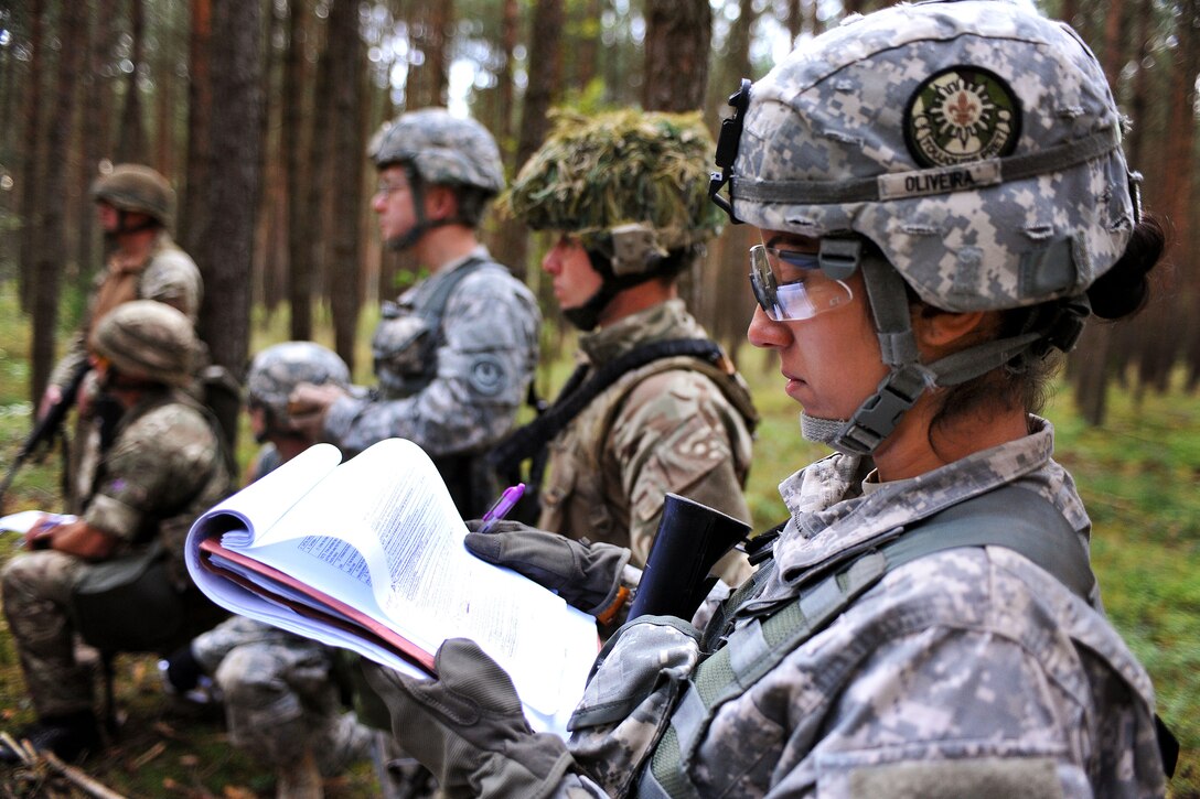 U.S. Army Capt. Andrea Oliviera, foreground, takes notes during the U.S. Army Europe Expert Field Medical Badge competition on the Joint Multinational Training Command's Grafenwoehr Training Area, Germany, Aug. 25, 2014. Oliviera is assigned to the 2nd Cavalry Regiment.