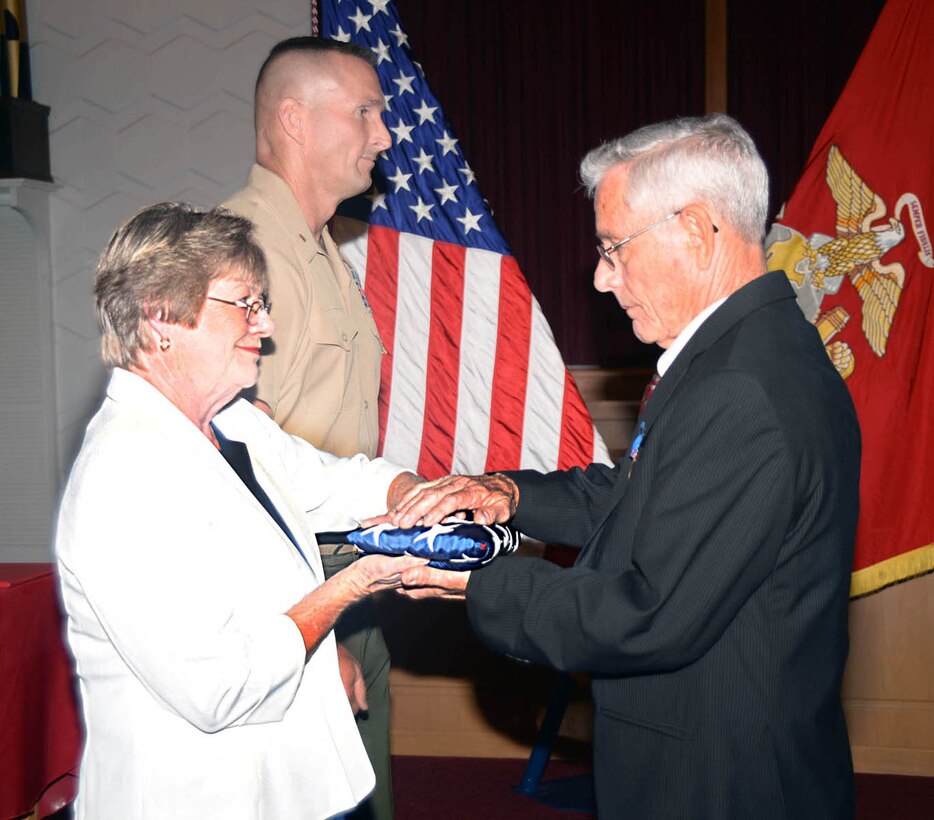 Both with Marine Corps Systems Command, Shirley Lemon presents Fred Day with a national ensign during his retirement ceremony Aug. 28 at the Chapel of the Good Shepherd, here. Day retired after nearly 40 years of military and civil service.