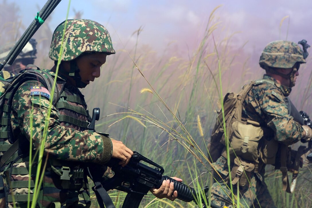 Marines with Echo Company, Battalion Landing Team 2nd Battalion, 1st Marines, 11th Marine Expeditionary Unit, and members of the Malaysian Armed Forces engage role-playing hostiles during a combined company-sized amphibious assault conducted between the forces as part of Malaysia-United States Amphibious Exercise 2014 Sept. 2. MALUS AMPHEX 14 is a bilateral exercise between the 11th MEU and Malaysian Armed Forces that includes operational and tactical level training in planning, command and control, and combat service support using both ground and sea assets. (U.S. Marine Corps photo by Sgt. Melissa Wenger/Released)