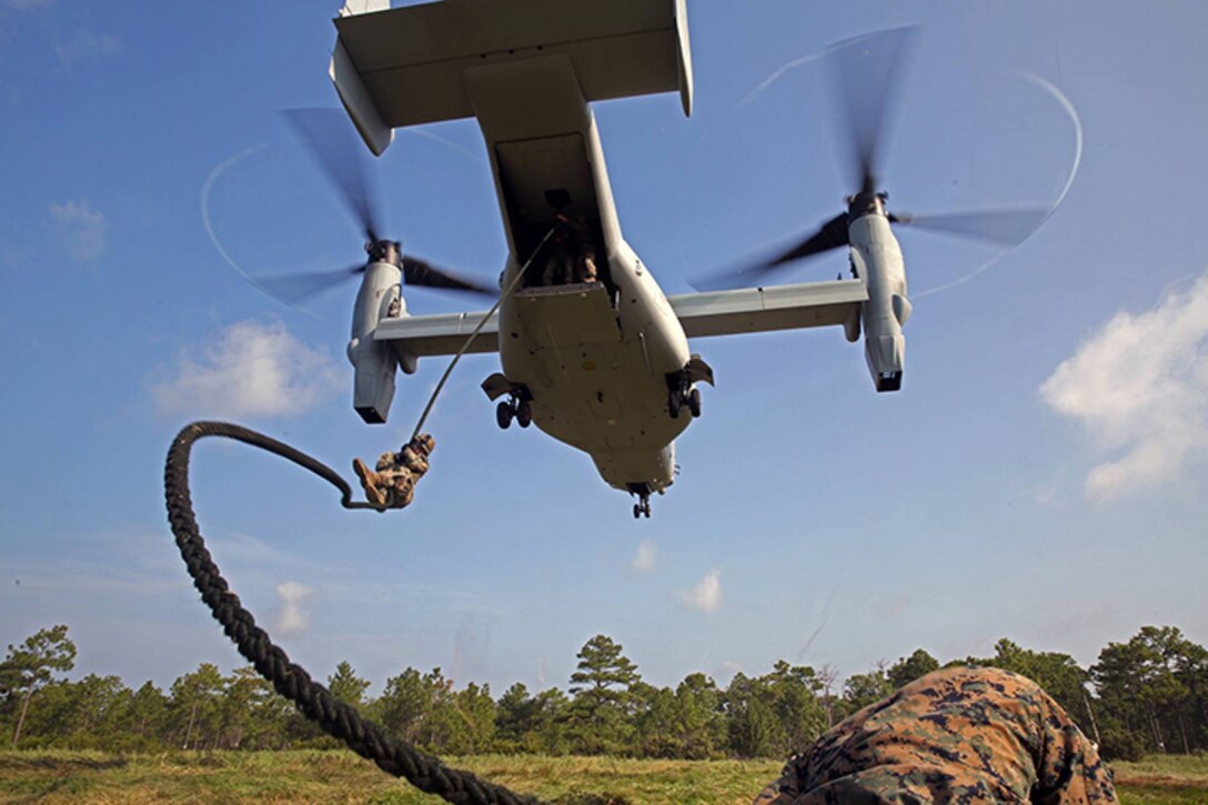 An MV-22B Osprey from Marine Medium Tiltrotor Squadron 365 (Reinforced), 24th Marine Expeditionary Unit, hovers as a Marine with Battalion Landing Team 3rd Battalion, 6th Marine Regiment, 24th MEU, descends a rope during Fast Rope Insertion Extraction System qualification at Camp Lejeune, N.C., August 22, 2014. Marines spent two days fast-roping from a tower and an MV-22B Osprey in preparation for their scheduled deployment at the end of the year. (U.S. Marine Corps photo by Sgt. Devin Nichols)