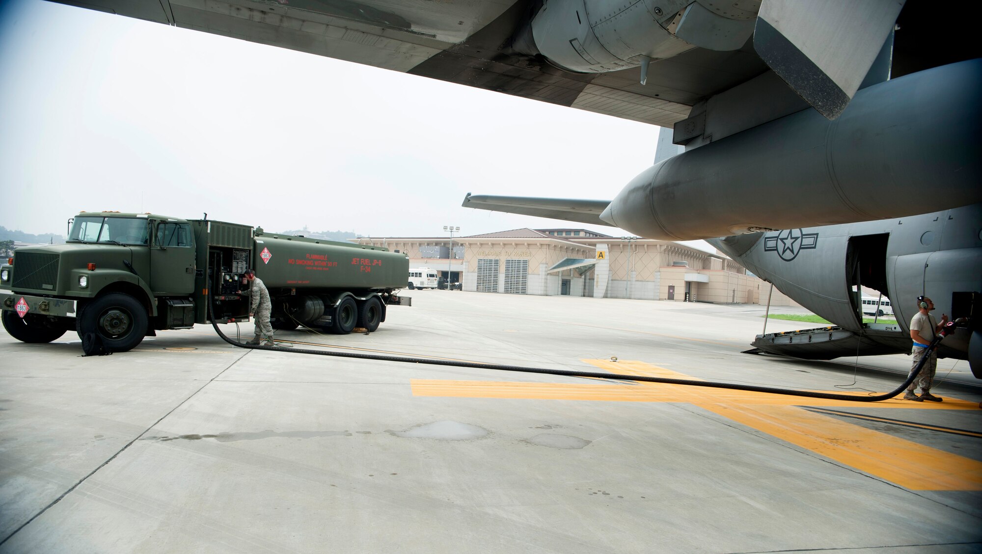 Airman 1st Class Jamie Groseclose, 51st Logistics Readiness Squadron fuels operator (left), fuels a C-130 Hercules while a C-130 crew chief monitors the fuel flow at Osan Air Base, Republic of Korea, Aug. 5, 2014. The fuels flight issues fuel to fighter jets within the 25th and 36th Fighter Squadrons as well as cargo and passenger transportation aircraft that fly in and out of the base. (U.S. Air Force photo by Senior Airman Matthew Lancaster/Released)