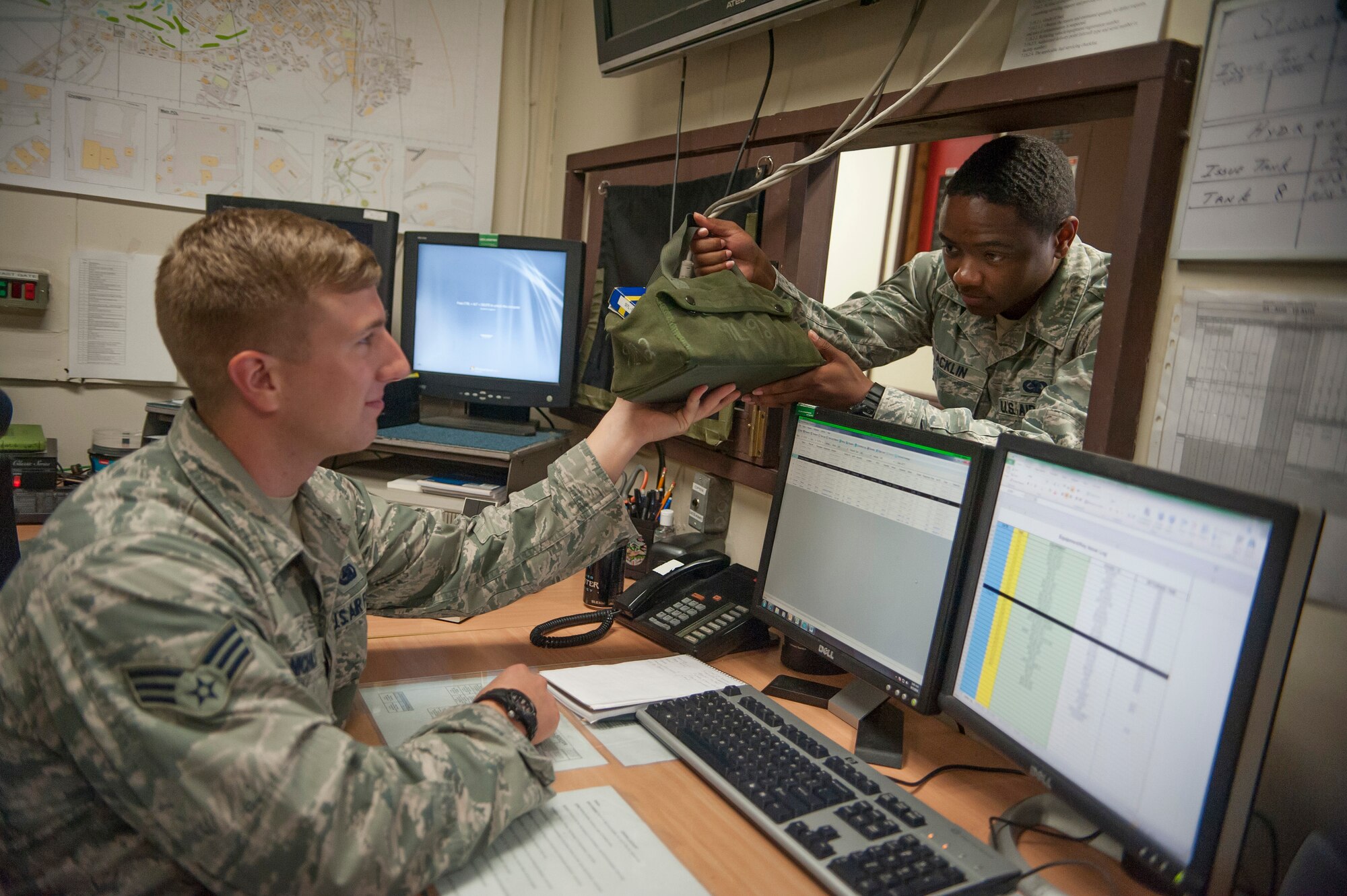Senior Airman Brian Nichols, 51st Logistics Readiness Squadron fuels controller (left), hands Staff Sgt. Lavandis Acklin, 51st LRS fuels controller, a fuels service kit at Osan Air Base, Republic of Korea, Aug. 5, 2014. Fuel controllers are in charge of keeping accountability for fight members during a recall, the fuel and equipment within the fight. (U.S. Air Force photo by Senior Airman Matthew Lancaster)
