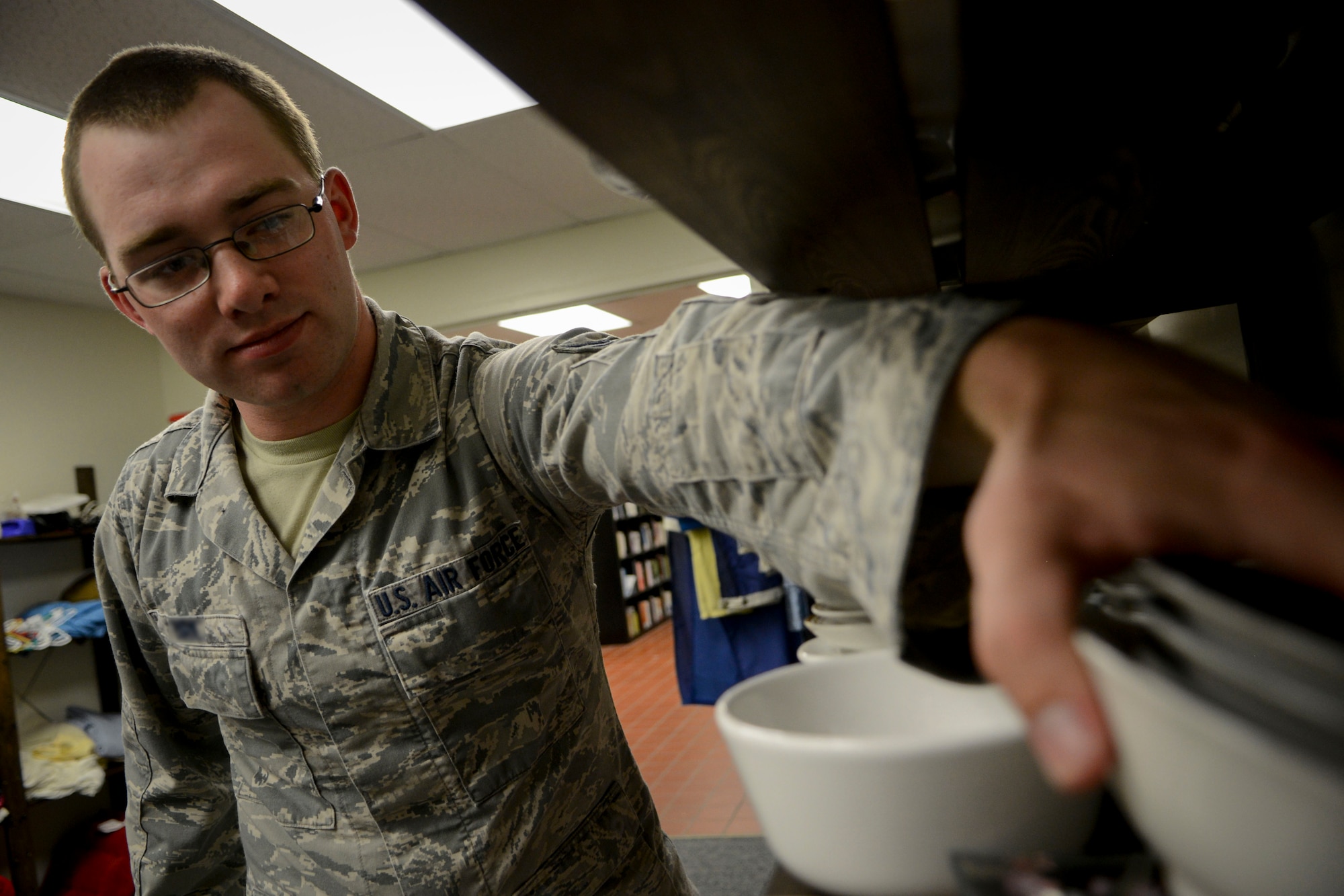 Airman 1st Class Colton, 9th Intelligence Squadron, looks for dishware at the Airman’s Attic on Beale Air Force Base, Calif., July 15, 2014. The Airman’s Attic is a place where E-7s and below, as well as 0-3s and below, can get free clothing and household items. During the fourth Saturday of every month the Airman’s Attic is open to all ranks. (U.S. Air Force photo by Senior Airman Shana Wojcik/Released)