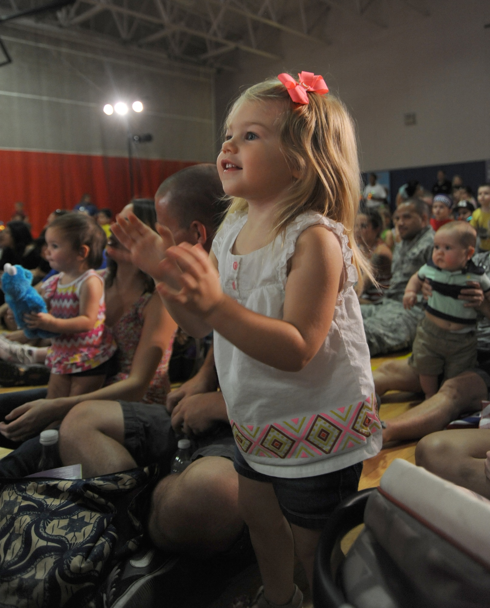 Madelyn Amos, 2, daughter of 2nd Lt. Tim Amos, 56th Operations Support Squadron, dances and claps while watching Sesame Street characters perform a minishow featuring Katie, a military kid on Sesame Street who is moving to a new place due to a parent’s permanent-change-of-station. The Sesame Street USO Experience for Military Families was held at the Luke Air Force Base Youth Center gym Aug. 19 and 20. The Sesame Street USO Experience for Military Families was created in 2008 to help service members and their families deal with the unique challenges they face, from deployments and homecomings to frequent relocations.‬‬ (U.S. Air Force photo/Denise Willhite)