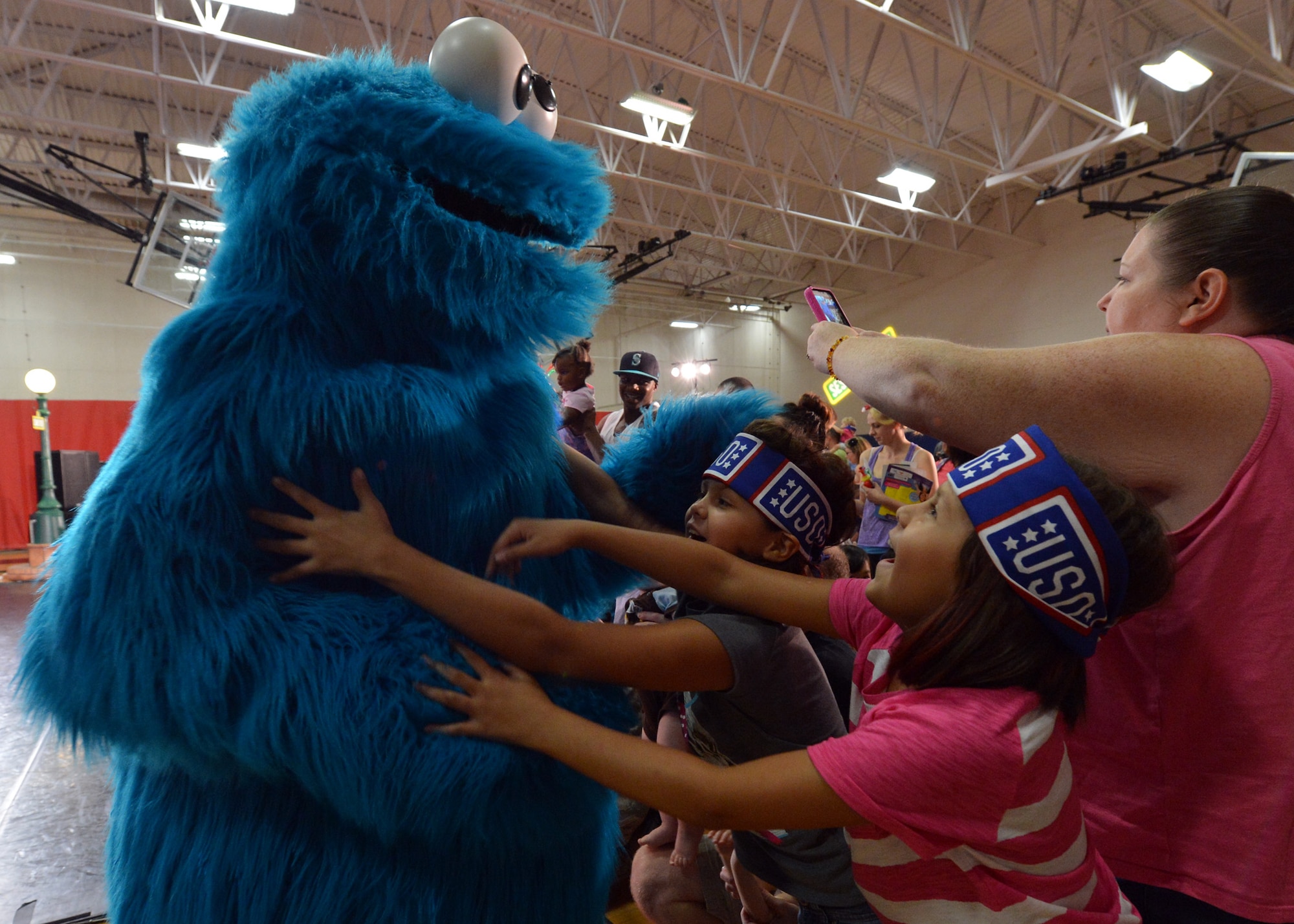 Cookie Monster, from Sesame Street, interacts with the crowd Aug. 19 during the Sesame Street USO Experience for Military Families performance at Luke Air Force Base. The show helped children understand that moving due to a permanent-change-of-station may be sad and difficult but keeping in touch with friends is fun and easy. (U.S. Air Force photo/Senior Airman Devante Williams)