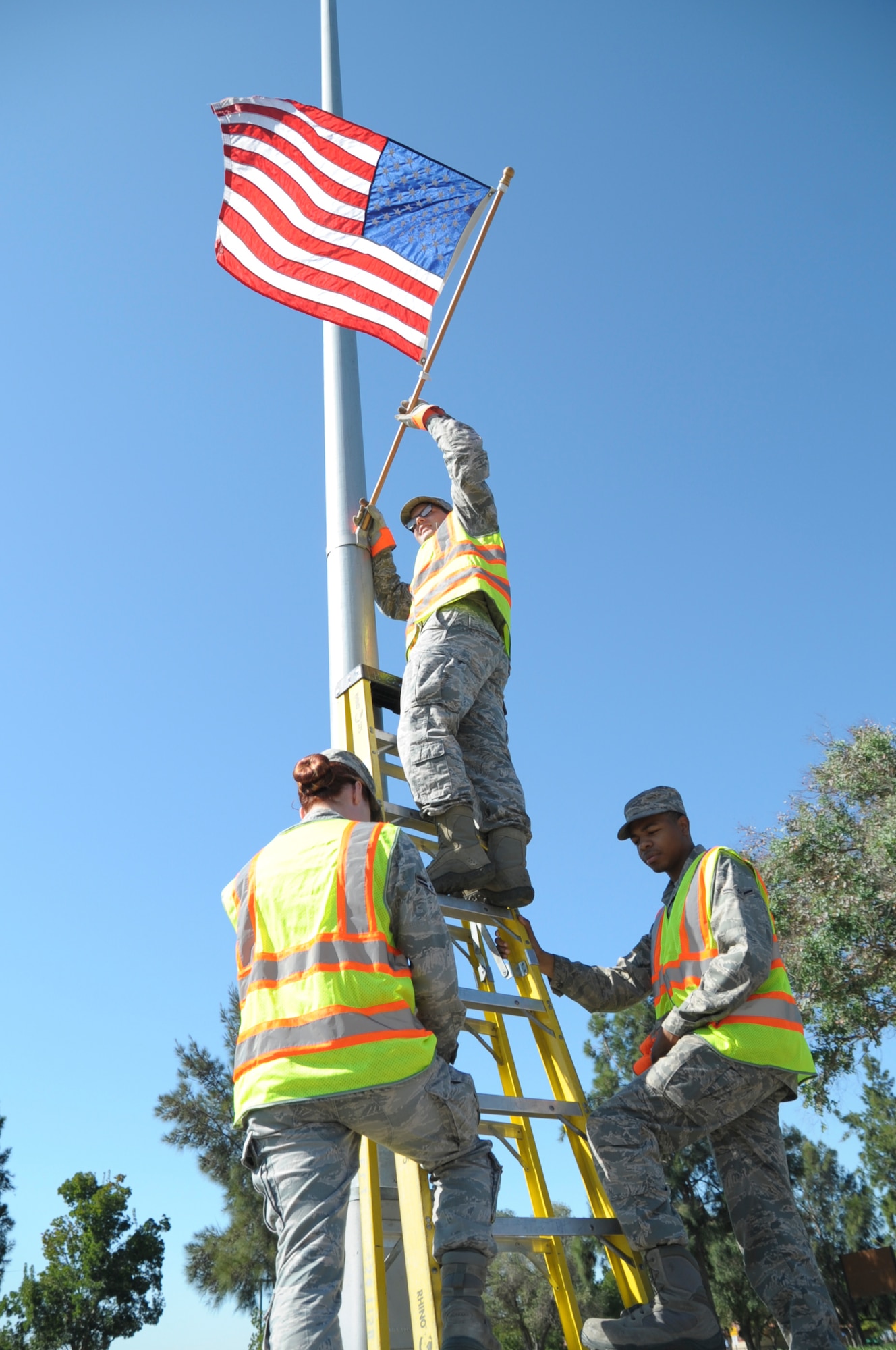 Airman 1st Class Jessica Duran, 60th Inpatient Operations Squadron mental health technician, Airman Dequan Bell, 60th Logistics Readiness Squadron warehouse technician and Senior Airman Zachary Burns, 60th Operations Support Squadron air traffic control and Base Appearance Team apprentice, hang a flag September 2 at Travis Air Force Base. The BAT hangs 98 U.S. flags for special events and holidays. (U.S. Air Force photo by Airman 1st Class Amber Carter)