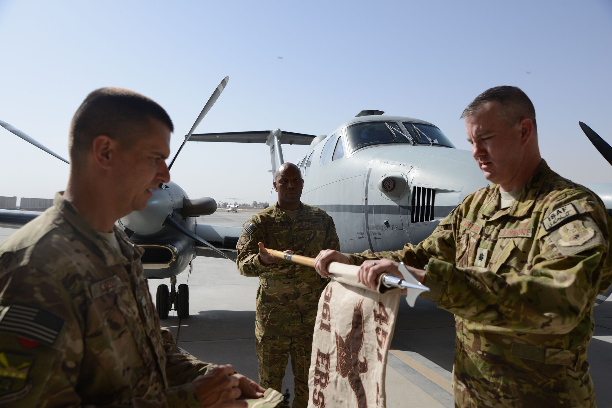 U.S. Master Sgt. Illyas Asaddullah, a sensor operator and acting 1st Sgt. for the 361st Expeditionary Reconnaissance Squadron holds the squadron’s guidon while Col. Rhude Cherry III, 451st Air Expeditionary Group commander, waits to sheath the guidon after Lt. Col James Mansard, 361st ERS commander, finishes rolling it up during the 361 ERS deactivation ceremony Sept. 1, 2014 at Kandahar Airfield, Afghanistan. The 361 ERS was responsible for providing over watch for the Regional Command-South and was responsible for scanning 57,000 kilometers of land, 700 convoys, 190 vehicle interdictions, 150 drug caches, 320 weapons caches and the removal of 890 enemies off the battlefield. (U.S. Air Force photo by Master Sgt. Cohen A. Young/Released)