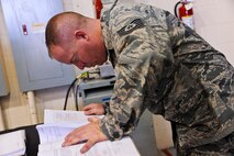 Tech. Sgt. Brian Dinkins, 341st Maintenance Operations Squadron power, refrigeration, and electrical assistant NCO in charge, references technical orders during a training session at Malmstrom Air Force Base’s 3-Bay Hangar Aug. 19. The technical orders, which include a schematic, show the location and amount of voltage that is applied to each wire located inside the guidance missile maintenance platform. (U.S. Air Force photo/Airman 1st Class Collin Schmidt)