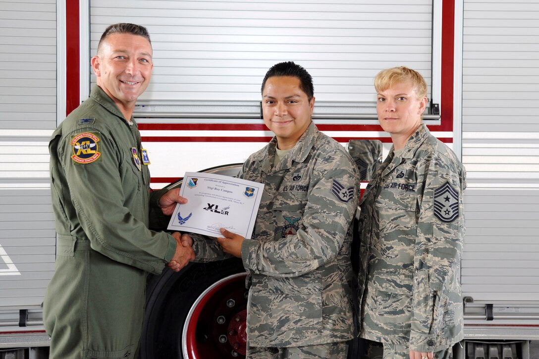 Staff Sgt. Roy Campos, center, 47th Civil Engineer Squadron Fire Department crew chief, poses with Col. Brian Hastings, left, 47th Flying Training Wing commander, and Chief Master Sgt. Teresa Clapper, right, 47th FTW command chief, after being presented the XLer of the week award here Sept. 3, 2014. The XLer is a weekly award chosen by wing leadership and given to those who consistently make outstanding contributions to their unit and Laughlin. (U.S. Air Force photo/Airman 1st Class Jimmie D. Pike)(Released)