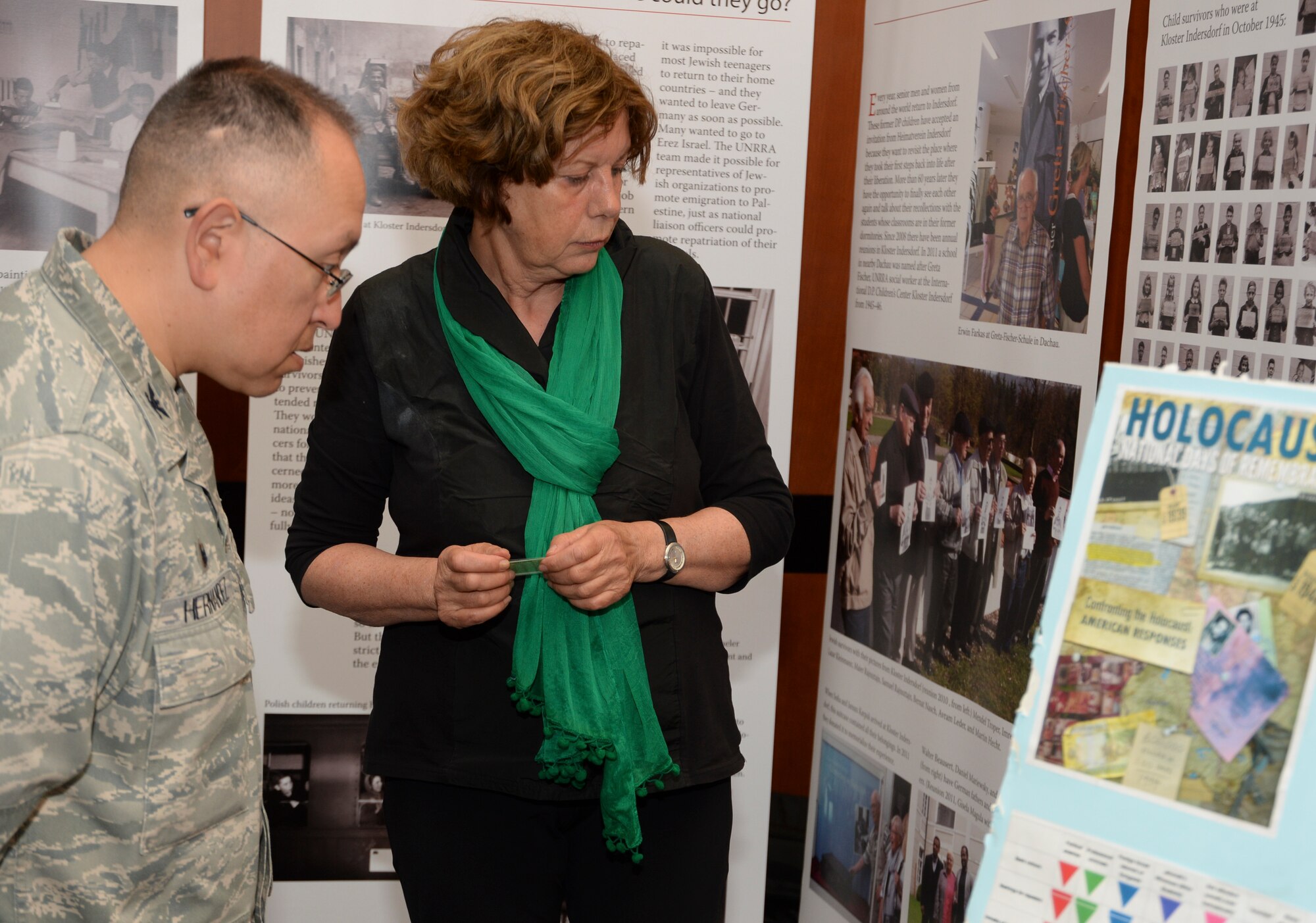 Anna Andlauer, an educator from Markt Indersdorf, Germany, center, speaks about a display on child survivors of the Holocaust to U.S. Air Force Col. Drysdale Hernandez, commander of the 52nd Mission Support Group, as part of the Diversity Day celebration at Club Eifel at Spangdahlem Air Base, Germany, Aug. 25, 2014. The displays and Andlauer’s presentation documented the care given to displaced Jewish and Gentile children following the Holocaust. (U.S. Air Force photo by Staff Sgt. Joe W. McFadden/Released)