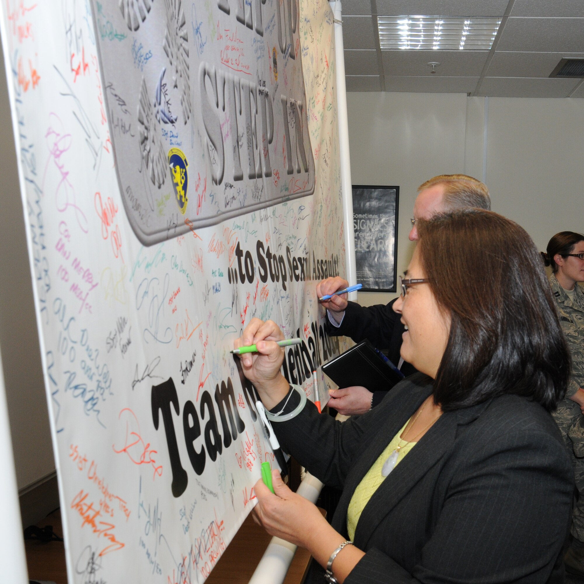 Debra Wada, front, subcommittee on military personnel minority lead and Dave Giachetti, subcommittee on military personnel, sign the sexual assault prevention and response “Step up, Step in” banner to show their pledge to support victims of sexual abuse Aug. 19, 2014, on RAF Mildenhall, England. Jeanette James, subcommittee on military personnel majority lead, also signed the banner during a visit to the sexual assault prevention and response center. (U.S. Air Force photo/Gina Randall/Released)