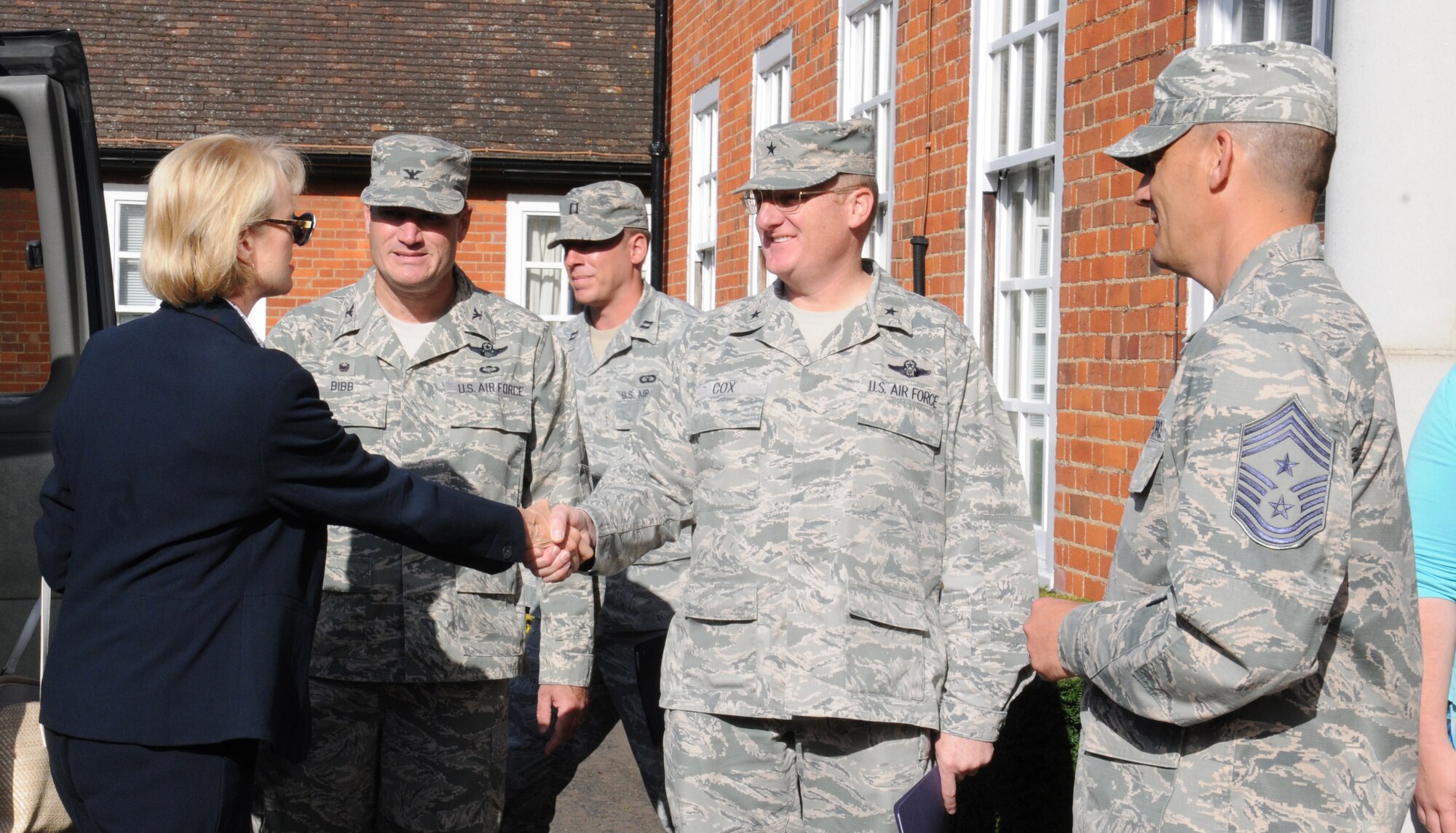 U.S. Air Force Brig. Gen. Douglas A. Cox, center, U.S. Air Forces in Europe-United Kingdom director, greets Jeanette James, subcommittee on military personnel majority lead, during a visit by members of Congress Aug. 19, 2014, on RAF Mildenhall, England. U.S. Air Force Col. Kenneth T. Bibb, Jr., second from left, 100th Air Refueling Wing commander, and U.S. Air Force Chief Master Sgt. Tracy Jones, right, 100th ARW command chief, also welcomed the distinguished guests to the wing headquarters building. (U.S. Air Force photo/Gina Randall/Released)