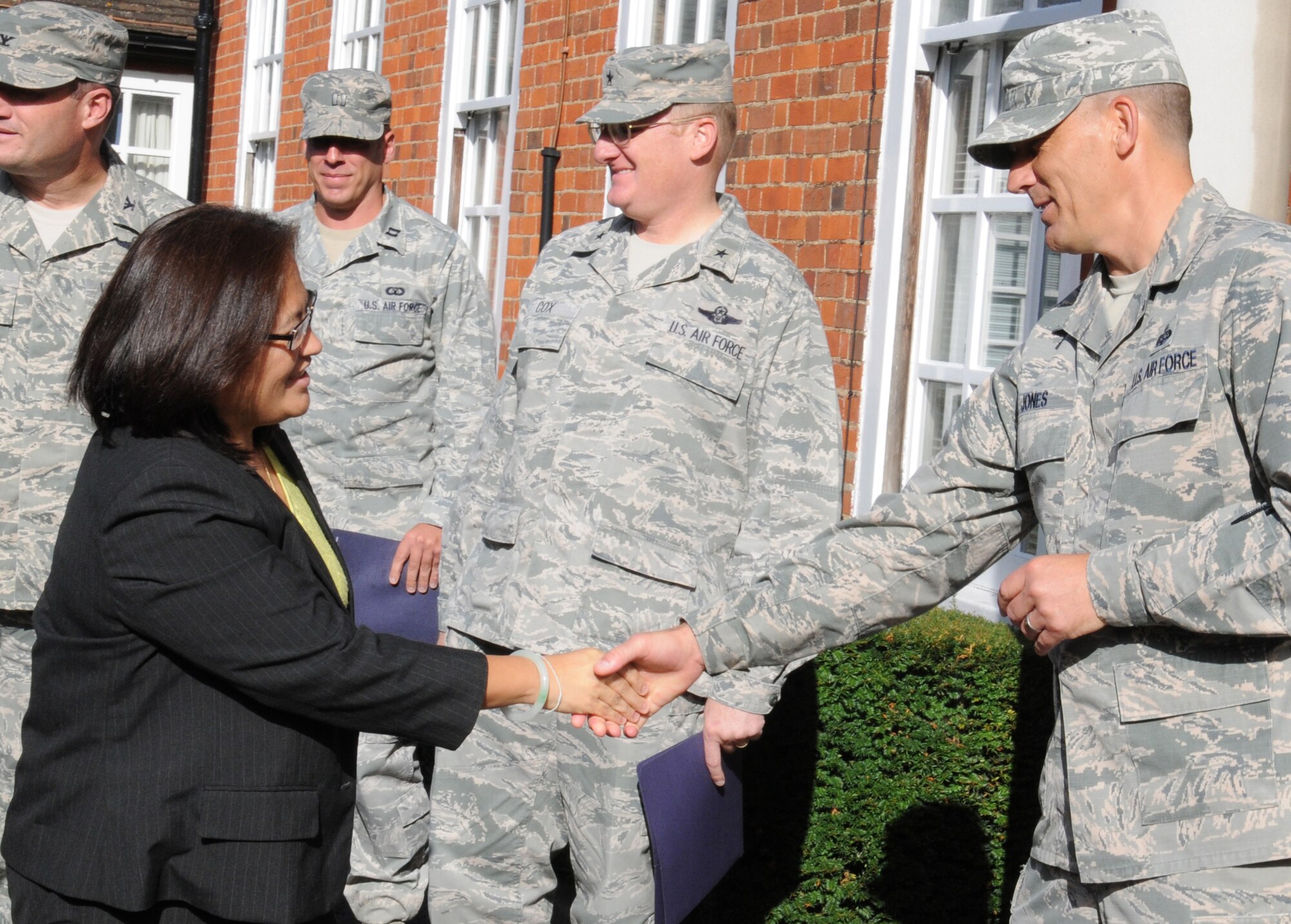 U.S. Air Force Chief Master Sgt. Tracy Jones, right, 100th Air Refueling Wing command chief, welcomes Debra Wada, subcommittee on military personnel minority lead, during a visit from Congress personnel Aug. 19, 2014, on RAF Mildenhall, England. U.S. Air Force Brig. Gen. Douglas A. Cox, second from right, U.S. Air Forces in Europe-United Kingdom director; U.S. Air Force Col. Kenneth T. Bibb, left, 100th Air Refueling Wing commander; and U.S. Air Force Capt. Joel Haarer, 100th Operation Support Squadron Airfield Operations Flight commander from Phoenix, Ariz., escorted the delegation during the visit. Wada; Jeanette James, subcommittee on military personnel majority lead; and Dave Giachetti, subcommittee on military personnel, were touring several bases in the United Kingdom including RAF Mildenhall and RAF Lakenheath. (U.S. Air Force photo/Gina Randall/Released)