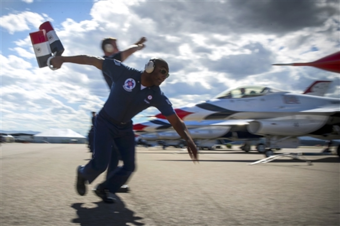 Air Force Staff Sgt. Francisco Garrigas prepares to chock Air Force Maj. Blaine Jones's F16 Fighting Falcon aircraft after returning from a performance during the Mountain Madness 2014 air show in Kalispell, Mont., Aug. 29, 2014. Garrigas is an assistant dedicated crew chief assigned to the Air Force Thunderbirds, the service's air demonstration team.