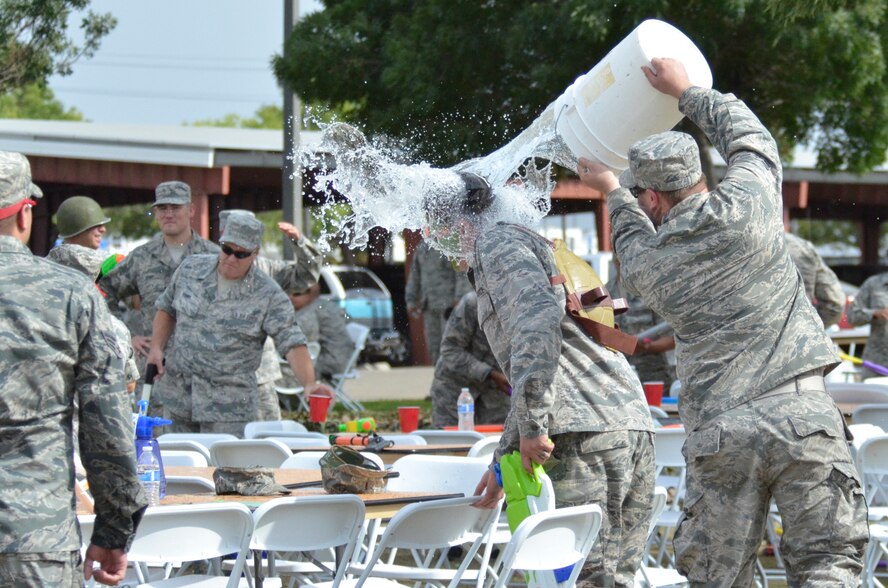 Airman 1st Class Michael Cavalli, 144th Maintenance Squadron egress mechanic, dumps a bucket of water on 2nd Lt. Jason Sanchez, 144th Fighter Wing Public Affairs officer, during the Combat Dining In Aug. 2, 2014. The Combat Dining In is an Air Force tradition that encourages camaraderie and morale. (Air National Guard photo by Airman 1st Class Klynne Pearl Serrano)