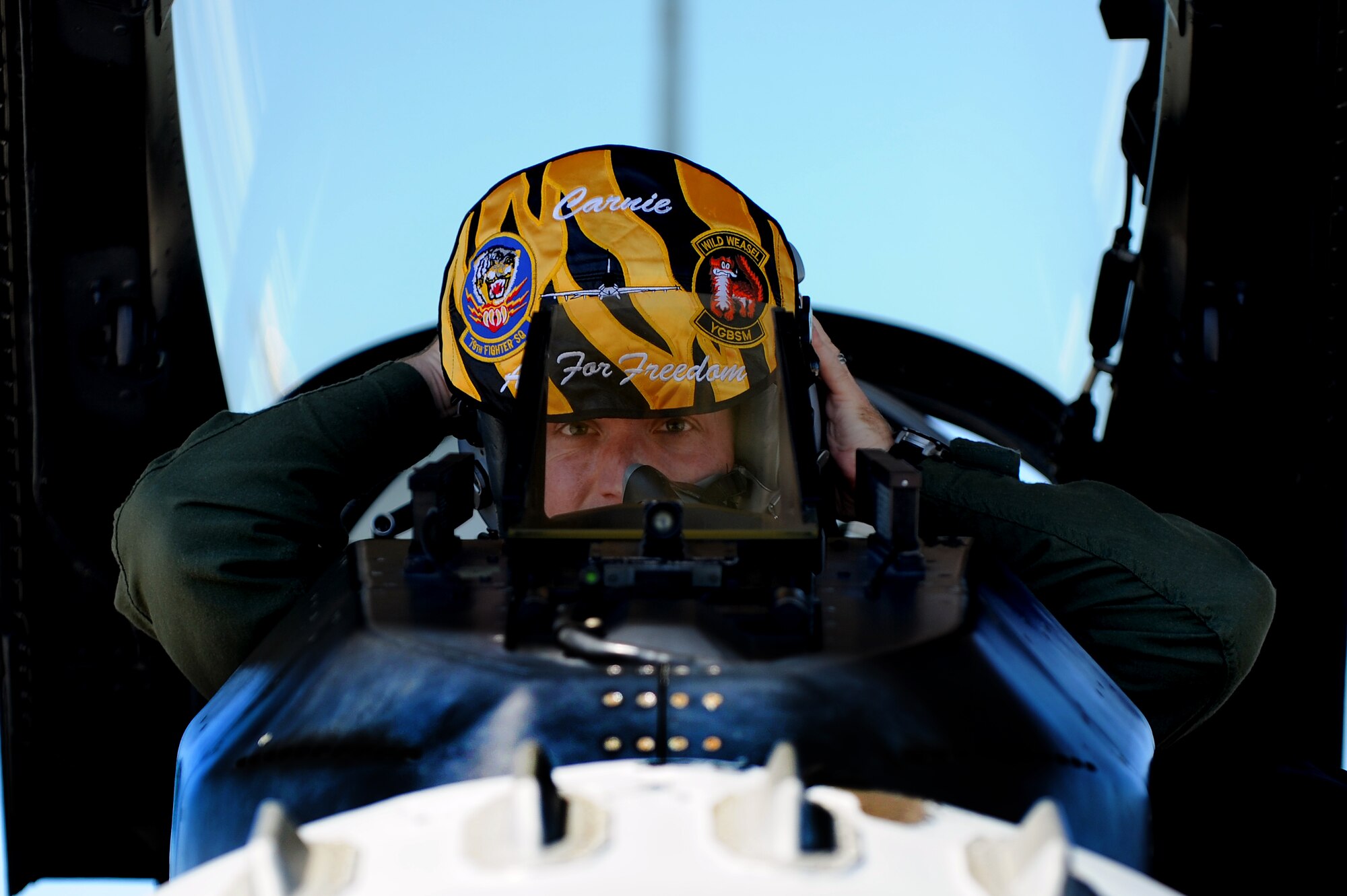 Royal Air Force Flight Lieutenant Benjamin Cable, 79th Fighter Squadron assistant director of operations, puts on his flight helmet in the cockpit of an F-16CM Fighting Falcon at Shaw Air Force Base, S.C., Aug. 27, 2014. Cable has been stationed at Shaw for approximately nine months as part of a military exchange program. (U.S. Air Force photo by Airman 1st Class Michael Cossaboom/Released)