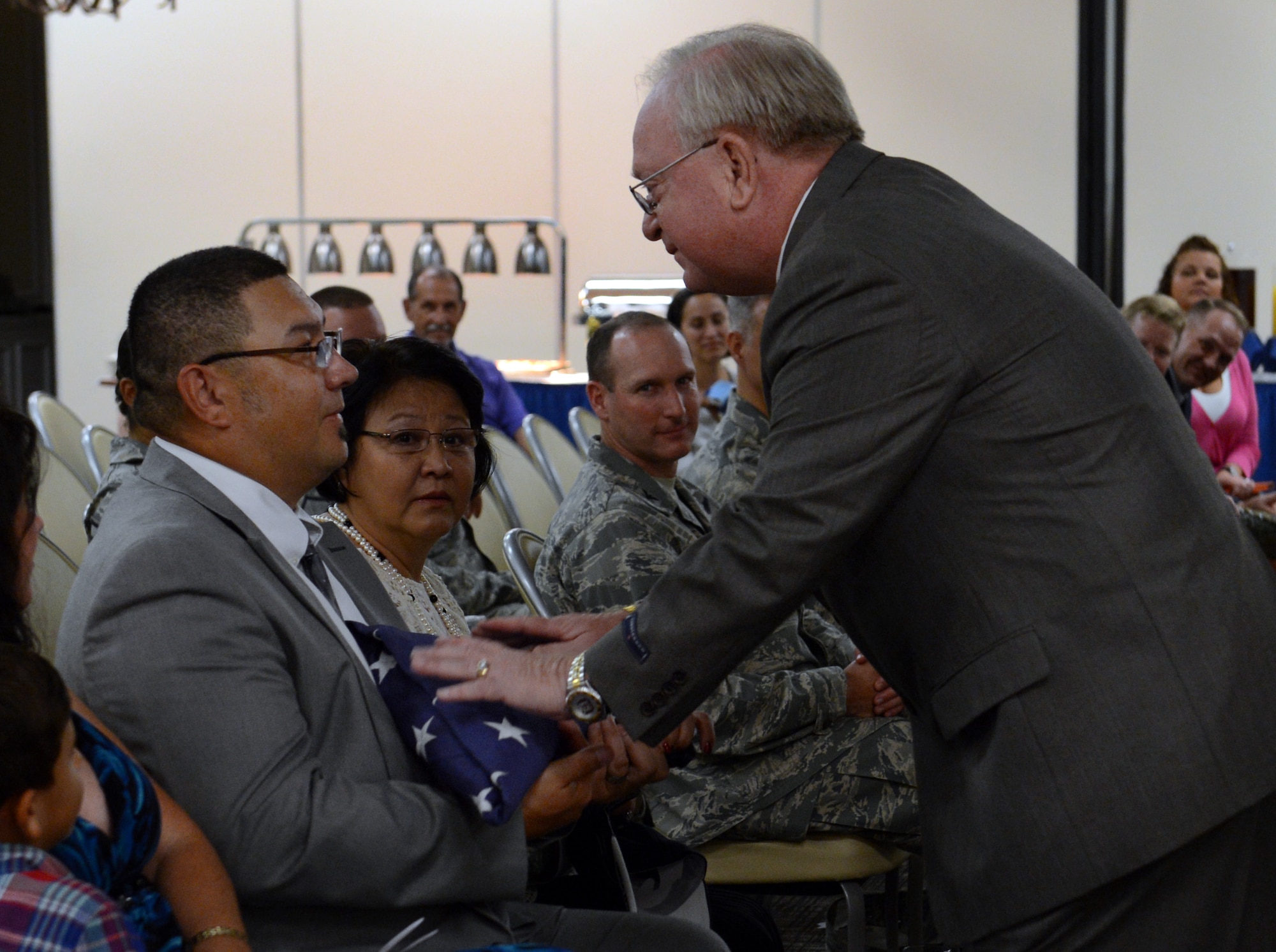 Retired U.S. Air Force Master Sgt. Bruce Pauly, 20th Logistics Readiness Squadron chief of passenger travel, gives his son James Pauly a folded American flag during Bruce’s retirement ceremony at the Carolina Skies Club and Conference Center, Shaw Air Force Base, S.C., Sept. 3, 2014. Family, friends and fellow Airmen gathered together to celebrate Bruce’s 39-year government career. (U.S. Air Force photo by Senior Airman Tabatha Zarrella/Released)
