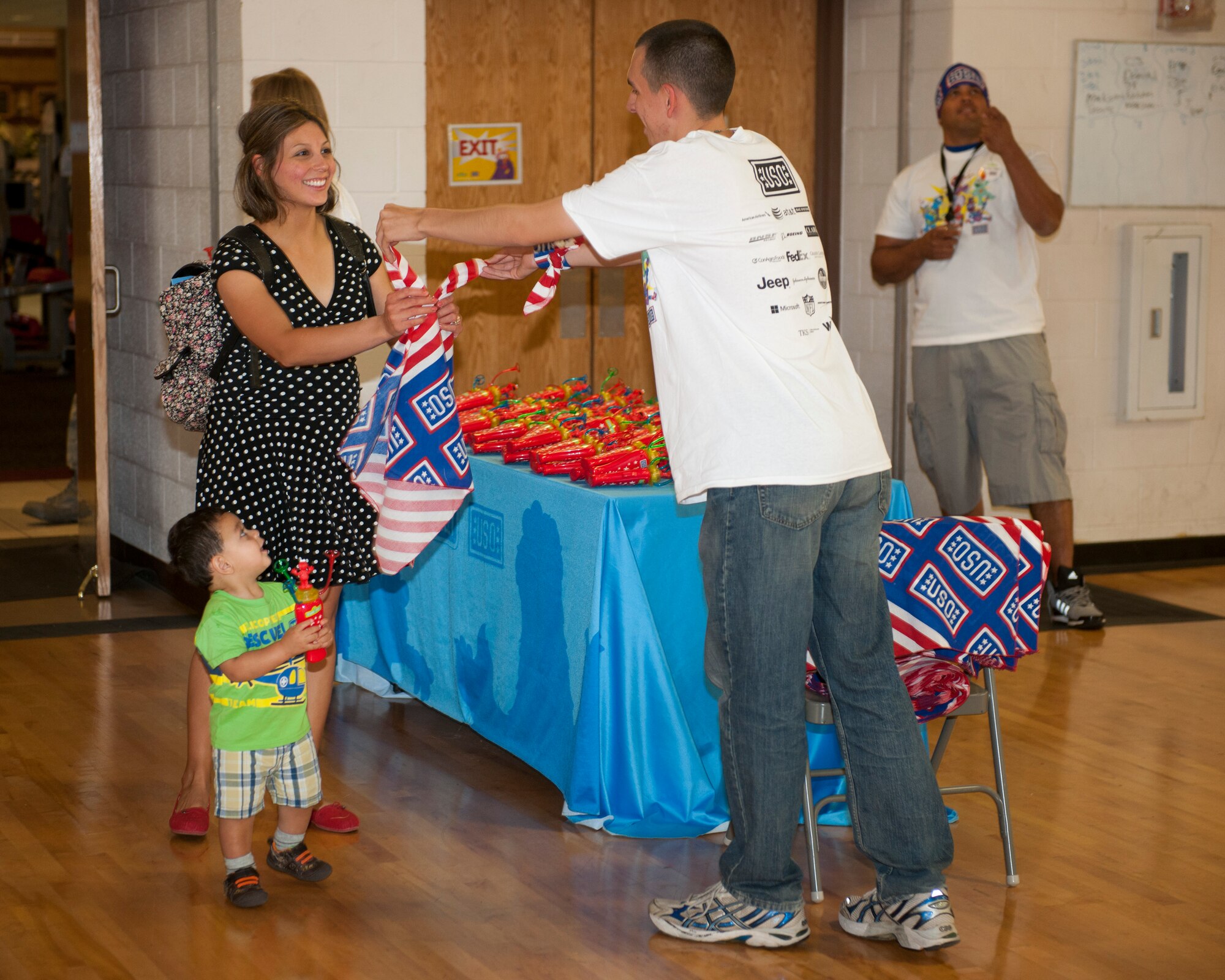 A Team Holloman family receives a bandana from a United Service Organizations volunteer Sept. 3, at Holloman Air Force Base, N.M. The USO presented the Sesame Street/USO Experience for Military Families to help create lasting memories for service members and their families, while dealing with challenges of military life. The 30-minute show consisted of three songs where Sesame Street characters sang, danced and interacted with families in the audience. (U.S. Air Force photo by Airman 1st Class Emily A. Kenney/ Released)