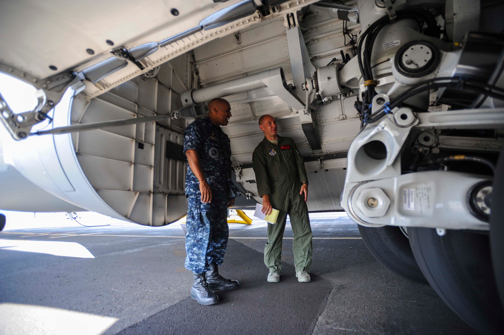 An operations controller from the 535th Airlift Squadron shows the C-17 Globemaster III wheel well to Navy. Capt. Stanley Keeve, Jr. on the JBPHH flightline during an immersion tour Sept. 4, 2014. Keeve was briefed by 15th Wing leaders and visited numerous squadrons to become familiar with the wing mission and operations. (U.S. Air Force photo by 1st Lt. Andrea Dykes)