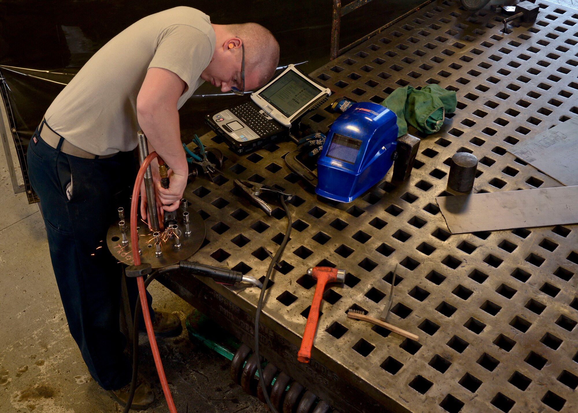 U.S. Air Force Senior Airman Spencer Chambers, 1st Maintenance Squadron aircraft metals technology journeyman, uses a tool to sand down rough edges on a nose and tire landing gear at Langley Air Force Base, Va., Sep. 3, 2014.  Sheet metals Airmen perform fabrication, structural repairs and modifications for aircraft. (U.S. Air Force photo by Senior Airman Connor Estes/Released)