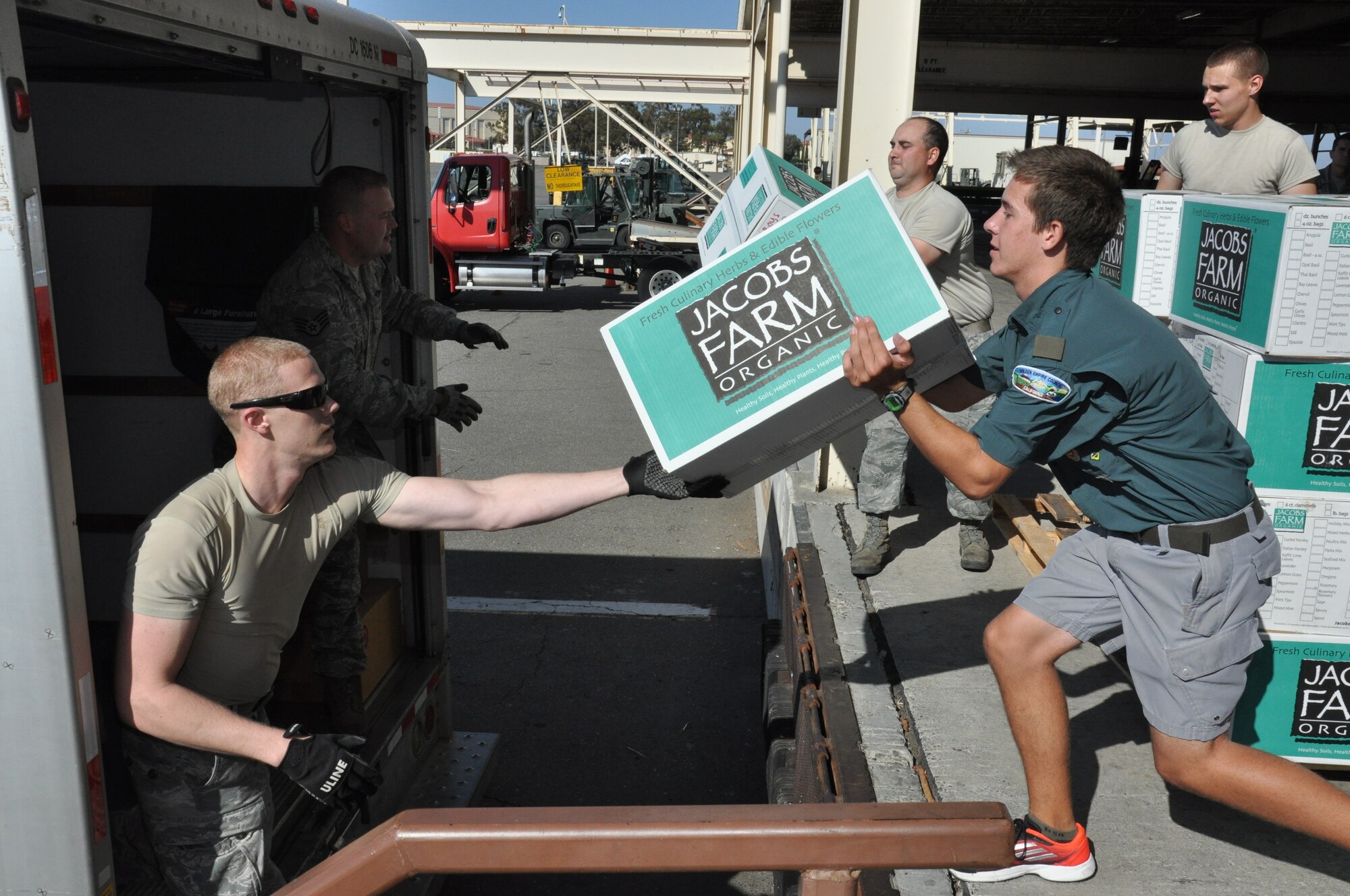 Senior Airman Kelby Williams, 60th Aerial Port Squadron traffic management officer, hands a box of donated goods to Andrew Reed, Boy Scout Troop 94 Eagle Scout candidate, as they and additional Airmen with the 60th APS off load a truck full of cargo Aug. 26 at Travis Air Force Base. (U.S. Air Force photo by Staff Sgt. Christopher Carranza)