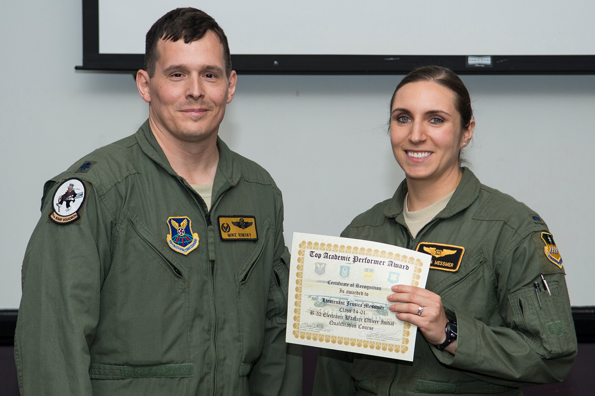 U.S. Air Force Lt. Col. Michael Rimsky, 11th Bomb Squadron commander, presents the Top Academic Performer Award to 1st Lt. Jessica Messmer during a graduation ceremony, Aug. 28, 2014, Barksdale Air Force Base, La. Messmer is a student of the B-52 Formal Training Unit class 14-01 and graduated with the highest academic scores in the Initial B-52 Electronic Warfare Officer Qualification course. (U.S. Air Force photo by Master Sgt. Greg Steele/Released)