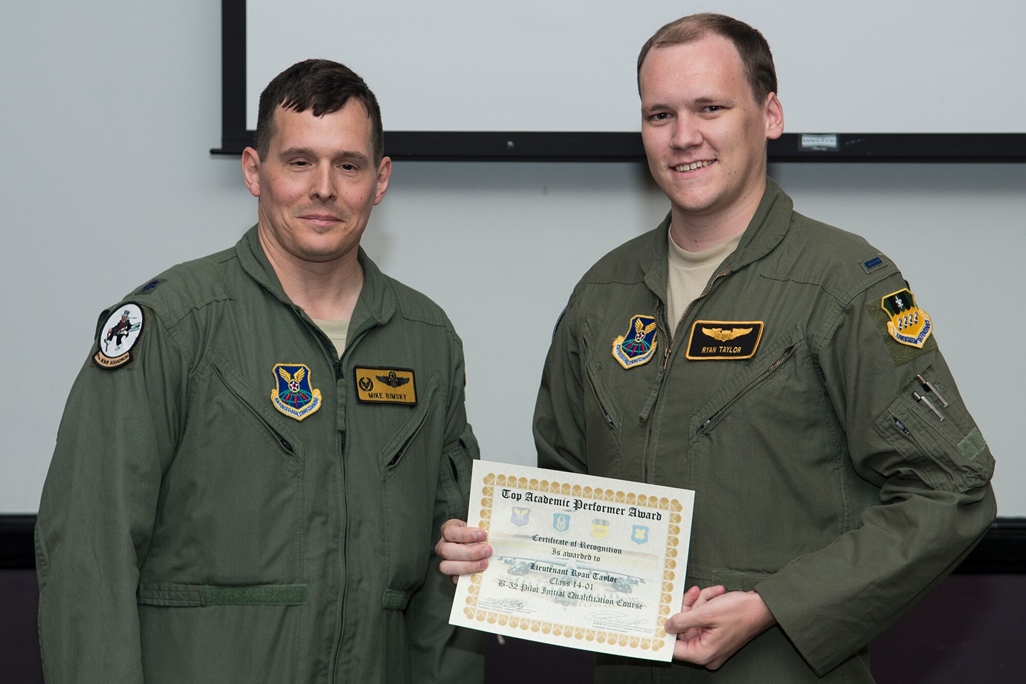 U.S. Air Force Lt. Col. Michael Rimsky, 11th Bomb Squadron commander, presents the Top Academic Performer Award to 1st Lt. Ryan Taylor during a graduation ceremony, Aug. 28, 2014, Barksdale Air Force Base, La. Taylor is a student of the B-52 Formal Training Unit class 14-01 and graduated with the highest academic scores in the Initial B-52 Pilot Qualification course. (U.S. Air Force photo by Master Sgt. Greg Steele/Released)