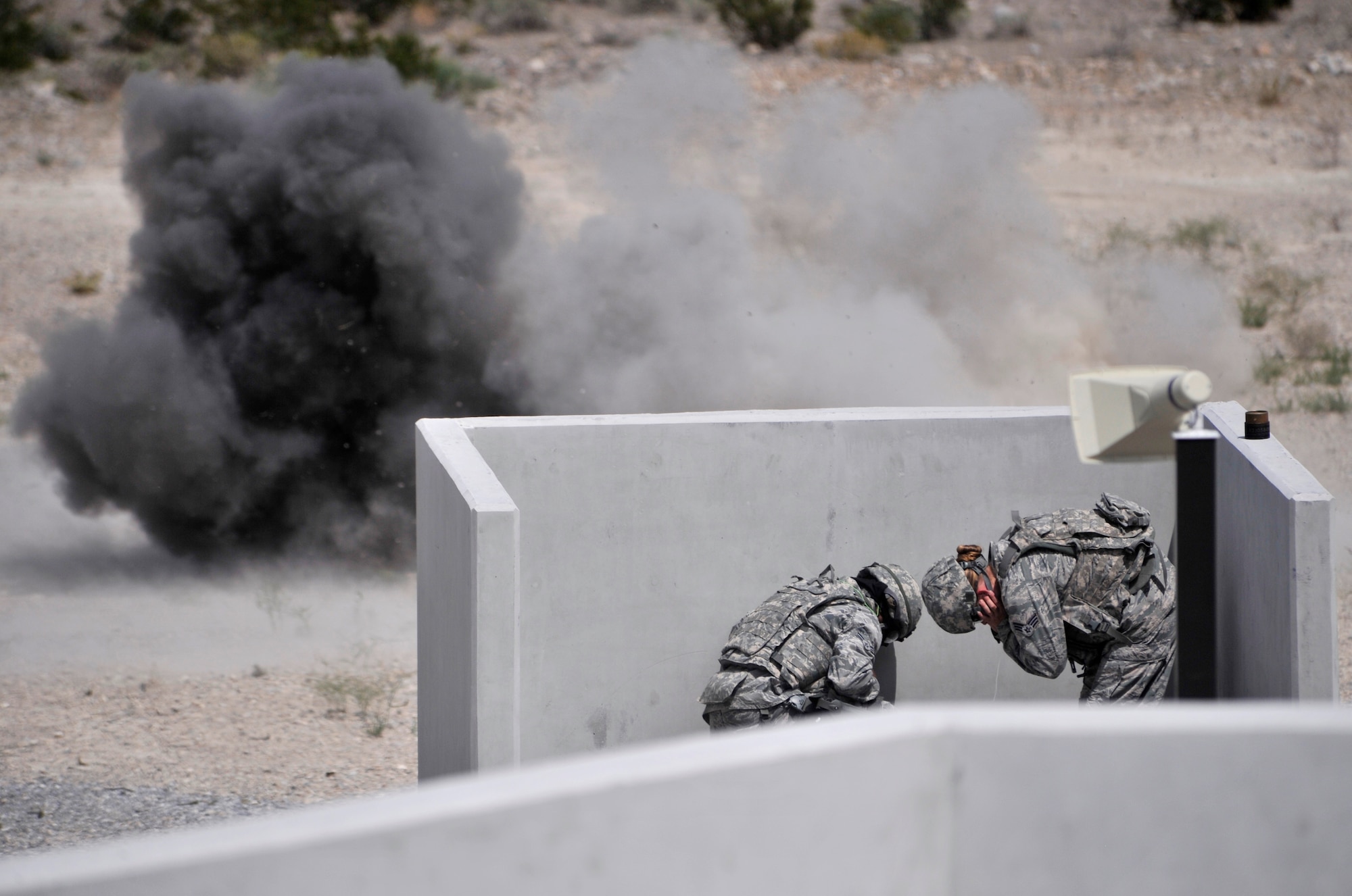 A student and instructor assigned to the 99th Ground Combat Training Squadron take cover behind a barrier during the last iteration of the M-67 fragmentation grenade training course Aug. 30, 2014, at Silver Flag Alpha, Nevada. The course has taken place at Silver Flag since 2011 and will be consolidated with the U.S. Army next year at Fort Bliss, Texas. (U.S. Air Force photo by Airman 1st Class Christian Clausen/Released)