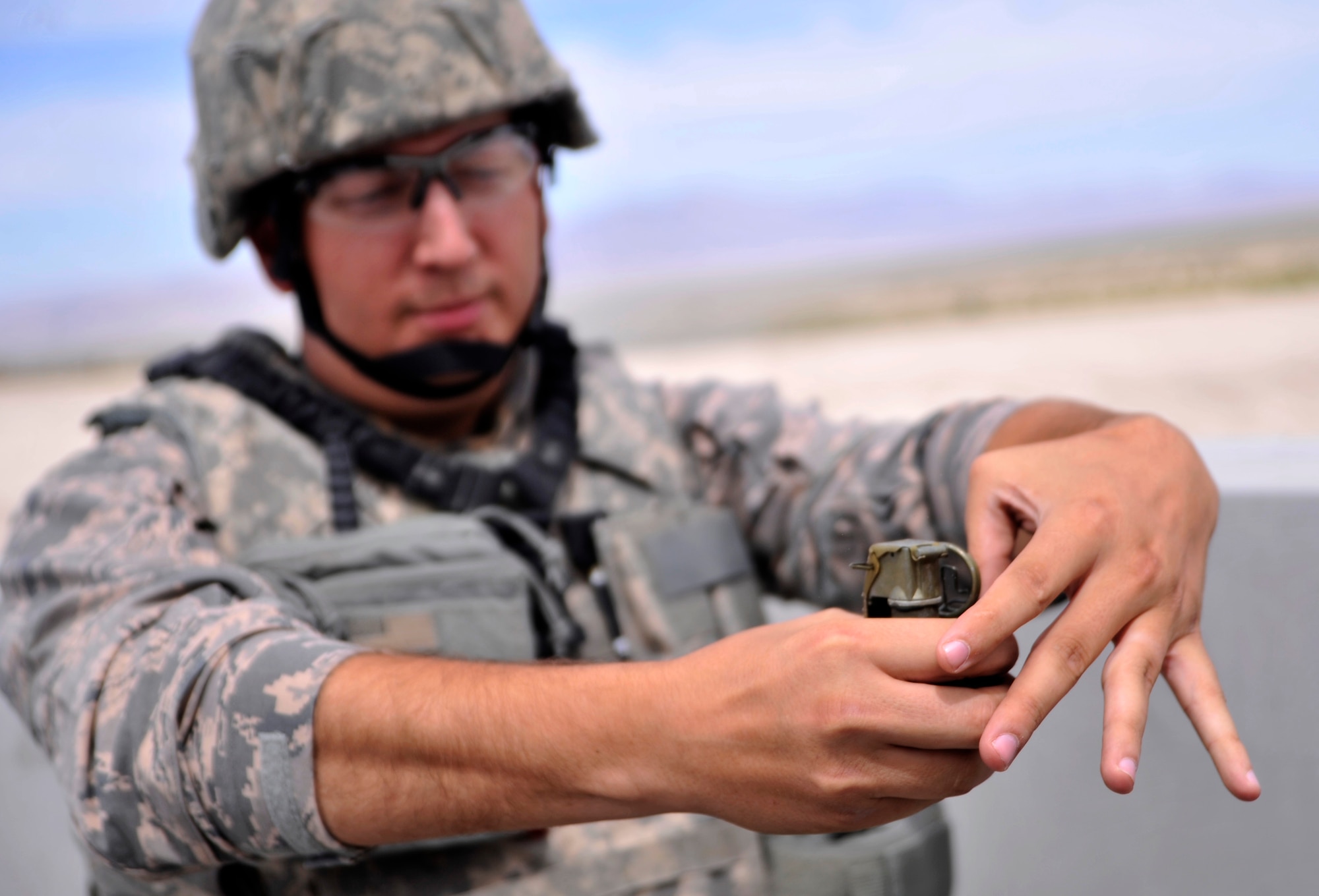 Tech. Sgt. Randall Disch, 99th Ground Combat Training Squadron Combat Arms instructor, releases the safety pin of an M-67 fragmentation grenade during the M-67 fragmentation grenade training class Aug. 30, 2014, at Silver Flag Alpha, Nevada. This is the last time the course will take place at Silver Flag. Next year the course will be consolidated with the U.S. Army at Fort Bliss, Texas. (U.S. Air Force photo by Airman 1st Class Christian Clausen/Released)