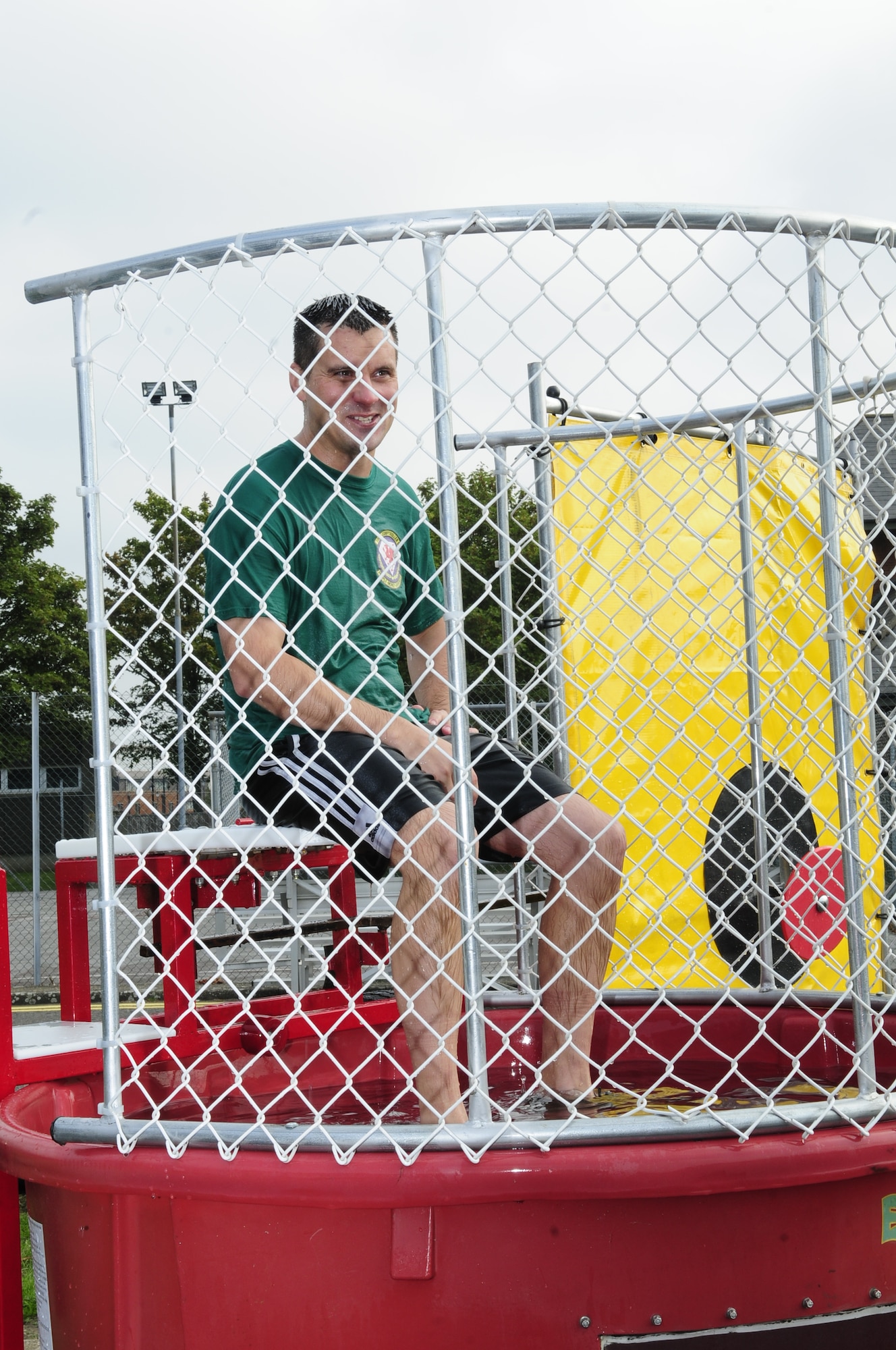 U.S. Air Force Lt. Col. Jason Holcomb, 100th Comptroller Squadron commander, sits ready for another soaking in the dunk tank at the Unaccompanied Airmen Appreciation Day Sept. 5, 2014, on RAF Mildenhall, England. Base leadership took turns getting dunked as Airmen threw balls to hit a target to send the commanders into a giant container of water. (U.S. Air Force photo/Karen Abeyasekere/Released)