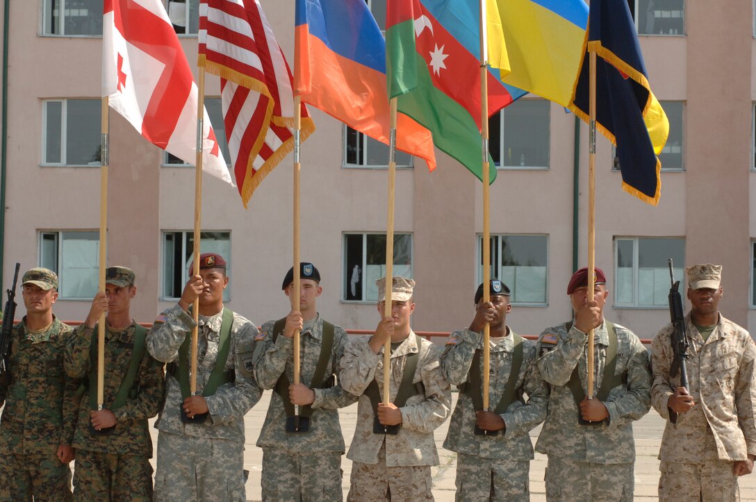 Georgian soldiers, left, with American Marines and soldiers, carry the flags of participating countries during Exercise Immediate Response, near Tbilisi, Georgia, August 2008. More than 900 American service members participated. U.S. Defense Secretary Chuck Hagel is making his first visit to Georgia as defense secretary during a September 2014 trip that also includes stops in Wales and Turkey. Georgia has served alongside the U.S. during operations and exercises.