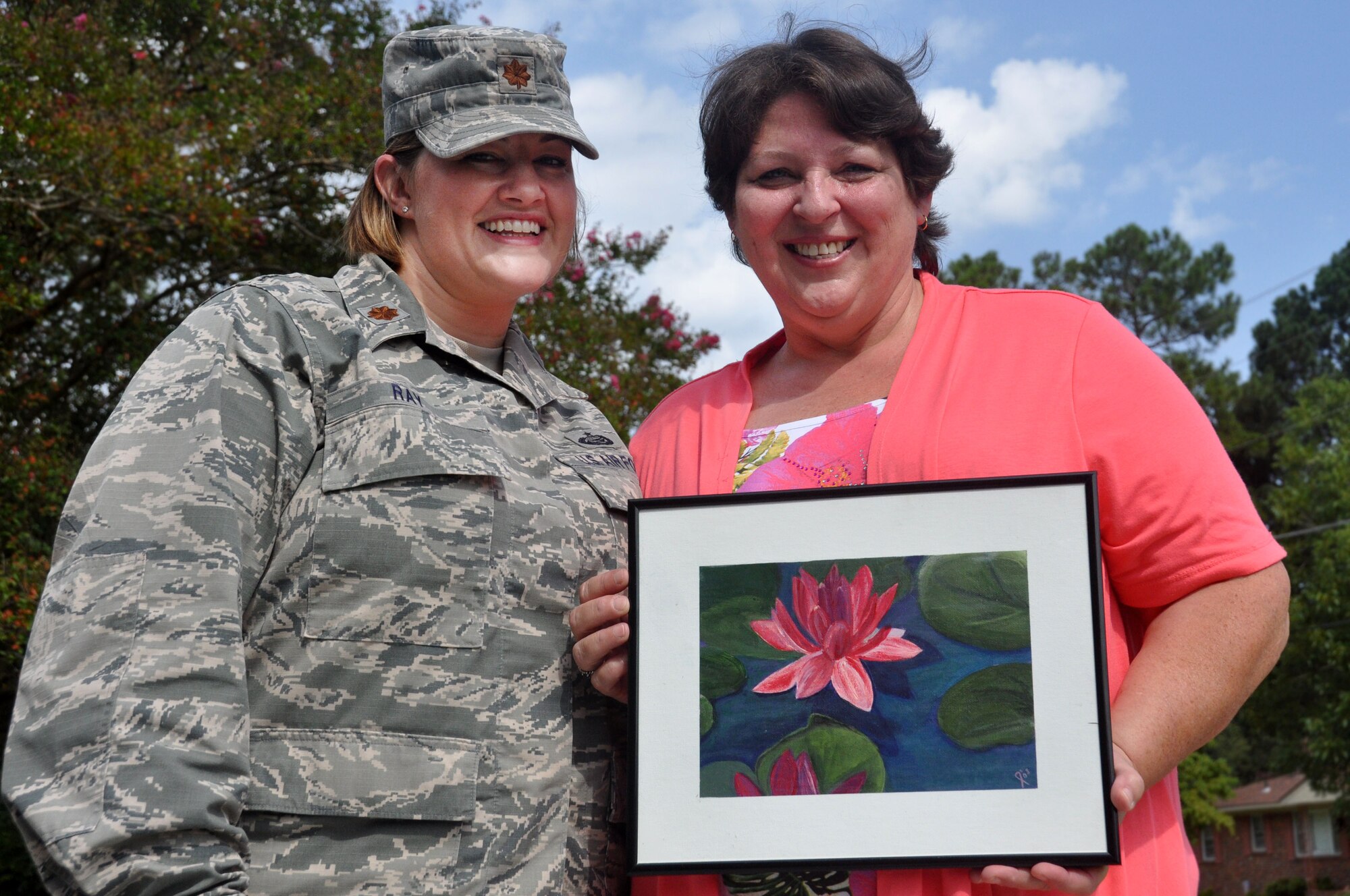 Maj. Lisa Ray, 440th Airlift Wing chief of Public Affairs, left, stands with her step mother Kathy Grantham who is a cancer survivor.  Grantham holds a painting she did as part of an art therapy program offered by the Friends of the Cancer Center, a non-profit Fayetteville organization that assists those fighting cancer.  (U.S. Air Force photo by Staff Sgt. Mark Thompson)
