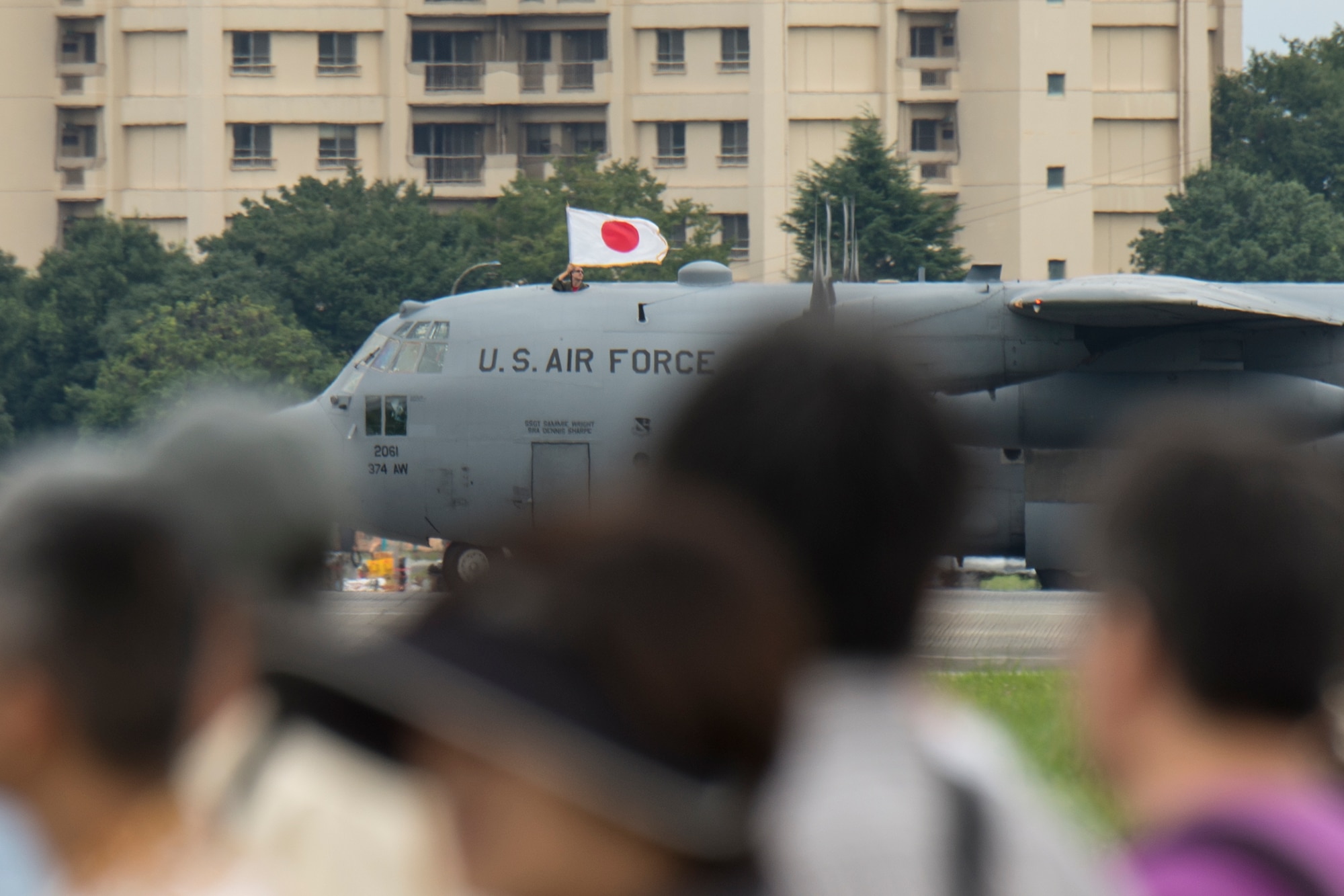 An Airman from the 36th Airlift Squadron holds a Japanese Flag atop a C-130 Hercules, assigned to the 36th Airlift Squadron at Yokota Air Base, Japan, during the Japanese-American Friendship Festival Sept. 7, 2014.  Paratroopers jumped from a C-130 as part of an aerial demonstration. (U.S. Air Force photo by Osakabe Yasuo/Released)
