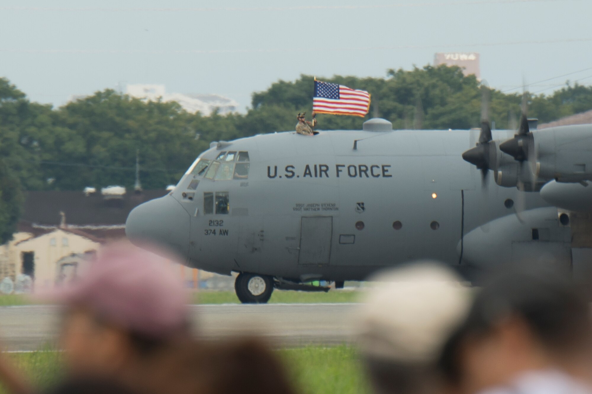 A U.S. Solider from the 1st Battalion, 1st Special Forces Group (Airborne) holds an American Flag outside of a C-130 Hercules assigned to the 36th Airlift Squadron at Yokota Air Base, Japan, during the Japanese-American Friendship Festival Sept. 7, 2014.  Paratroopers jumped from a C-130 as part of an aerial demonstration. (U.S. Air Force photo by Osakabe Yasuo/Released)