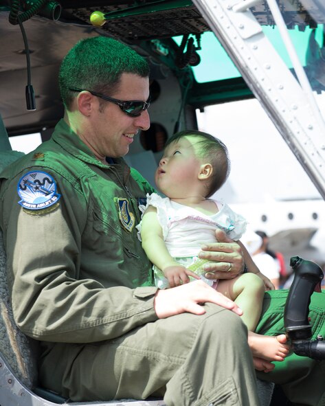 Maj. TJ Martin, 459th Airlift Squadron UH-1N pilot, carries a local baby at Yokota Air Base, Japan, during the Japanese-American Friendship Sept. 6, 2014. Yokota welcomed approximately 148,000 visitors during the two-day festival. (U.S. Air Force photo by Osakabe Yasuo/Released) 