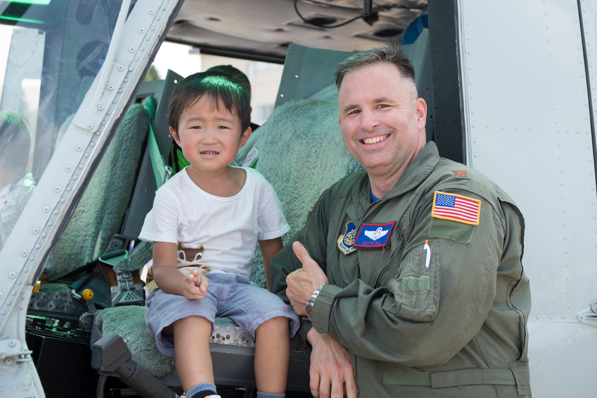 Maj. Destry Hill, UH-1N Iroquois pilot and 5th Air Force assistant director of operation, poses for photos with a local boy at Yokota Air Base, Japan, during the Japanese-American Friendship Festival Sept. 6, 2014. The festival is designed to bolster the bi-lateral relationship shared by the United States and Japan. (U.S. Air Force photo by Osakabe Yasuo/Released)