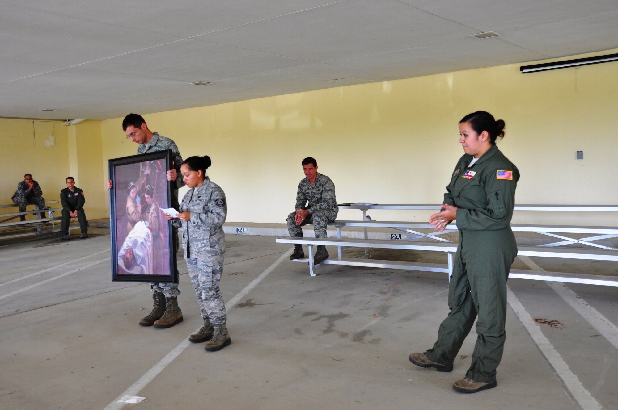 Senior Airman Michael Romer, a 433rd Aeromedical evacuation Squadron flight medic, holds the Bandage 33 portrait during its presentation to the unit on September 7, 2014 at Joint Base San Antonio-Lackland, Texas. Tech. Sgt. Kim Herrera, 433rd Airlift Wing historian, read the story behind the portrait.  Col. William Whittenberger, Jr., 433rd Airlift Wing commander, looks on as Staff Sgt. Amanda Torres, 433rd AES flight medic, was honored. Torres is one of the two 433rd AES medical personnel portrayed saving the life of a Air Force Combat Controller in the portrait. (U.S. Air Force Photo by Tech Sgt. Carlos J. Trevino)