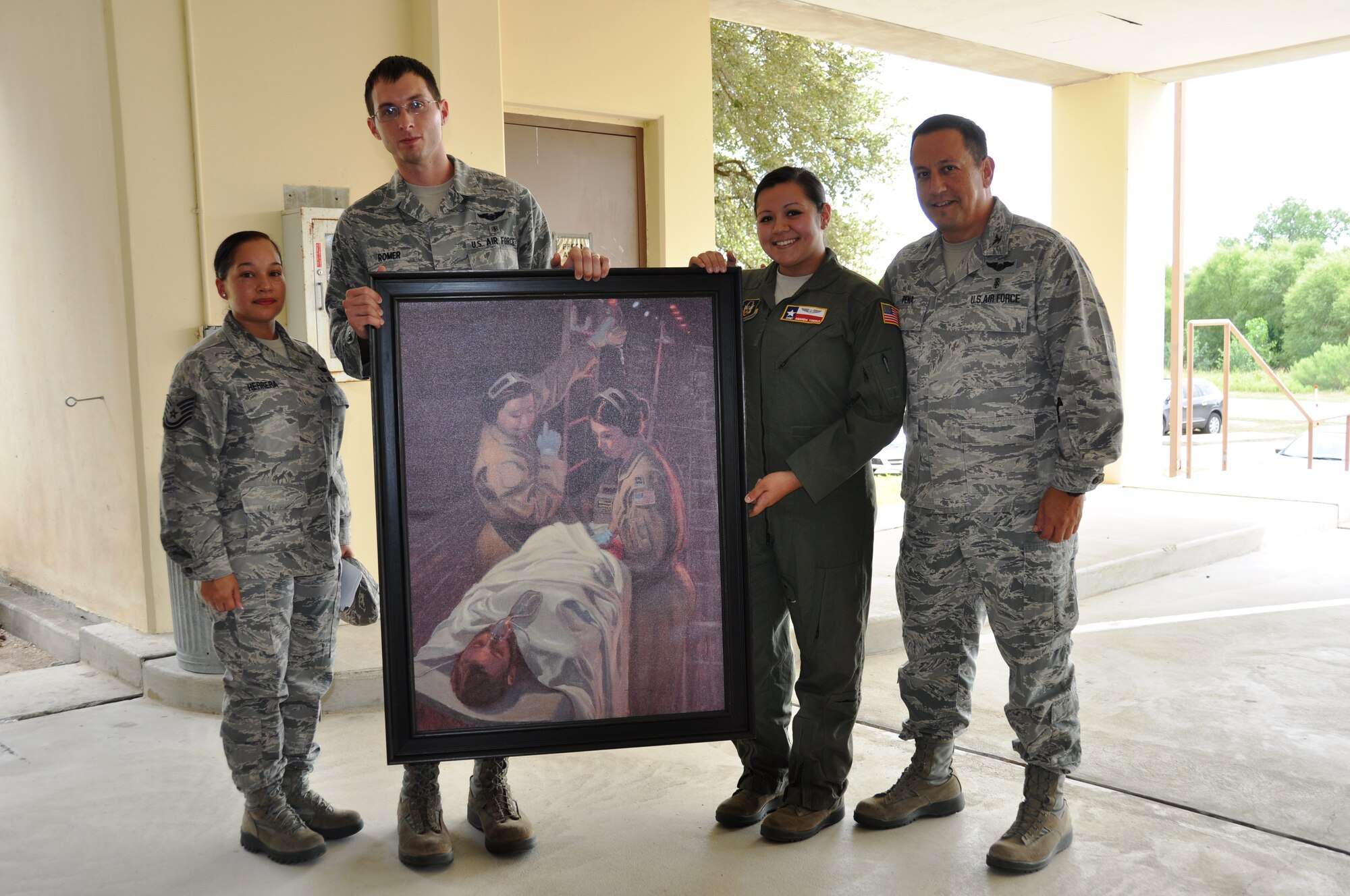 Senior Airman Michael Romer, a 433rd Aeromedical evacuation Squadron flight medic, holds the Bandage 33 portrait at the presentation on September 7, 2014 at Joint Base San Antonio-Lackland, Texas.Tech. Sgt. Kim Herrera, 433rd Airlift Wing historian (left), and Staff Sgt. Amanda Torres, 433rd Aeromedical Evacuation Squadron flight medic, and Col. Anthony Pena, 433rd Medical Squadron commander, who is Sergeant Torres' father. Torres is one of the two medical personnel portrayed saving the life of a Air Force Combat Controller. (U.S. Air Force Photo by Tech Sgt. Carlos J. Trevino)
