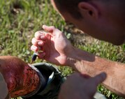 A 96th Medical Group moulage team member applies fake blood to a victim’s leg wound prior to a recent exercise at Duke Field.  The 96th MDG’s team of six Airmen provides a sense of realism in exercises that medics and first responders may encounter in real-world accidents. (U.S. Air Force photo/Tech. Sgt. Jasmin Taylor)