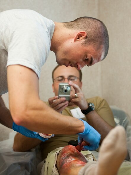 Staff Sgt. Tim Nelson, 96th Medical Group, applies some blood texture to the 919th Special Operations Wing's Staff Sgt. Josh Rix’s leg prior to a recent exercise at Duke Field.  The 96th MDG’s team of six Airmen provides a sense of realism in exercises that medics and first responders may encounter in real-world accidents. (U.S. Air Force photo/Tech. Sgt. Samuel King Jr.)