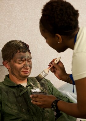 Master Sgt. Michael Sims, 5th Special Operations Squadron, gets a “dusting” of ash make up by Senior Airman LaAnn Coleman, 96th Medical Group, prior to a recent exercise at Duke Field.  The 96th MDG’s team of six Airmen provides a sense of realism in exercises that medics and first responders may encounter in real-world accidents. (U.S. Air Force photo/Tech. Sgt. Jasmin Taylor)