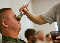 Senior Airman Christianson Parker, 919th Special Operations Support Squadron, gets a “dusting” of ash make up by a moulage team member prior to a recent exercise at Duke Field.  The 96th Medical Group's team of six Airmen provides a sense of realism in exercises that medics and first responders may encounter in real-world accidents. (U.S. Air Force photo/Tech. Sgt. Samuel King Jr.)